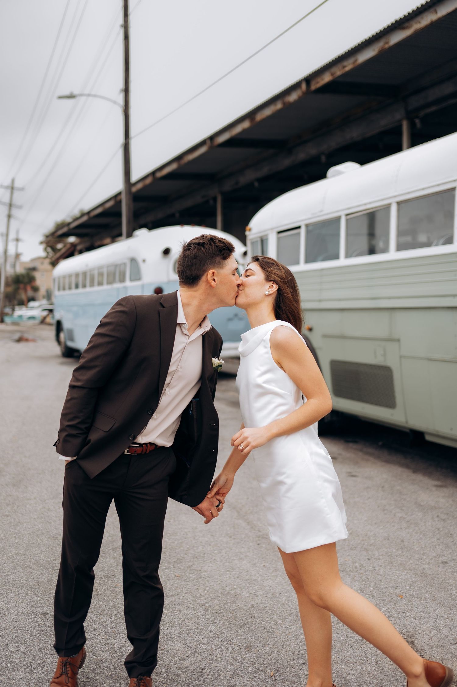 Couple in black suit and white dress share romantic dance moves in urban setting.