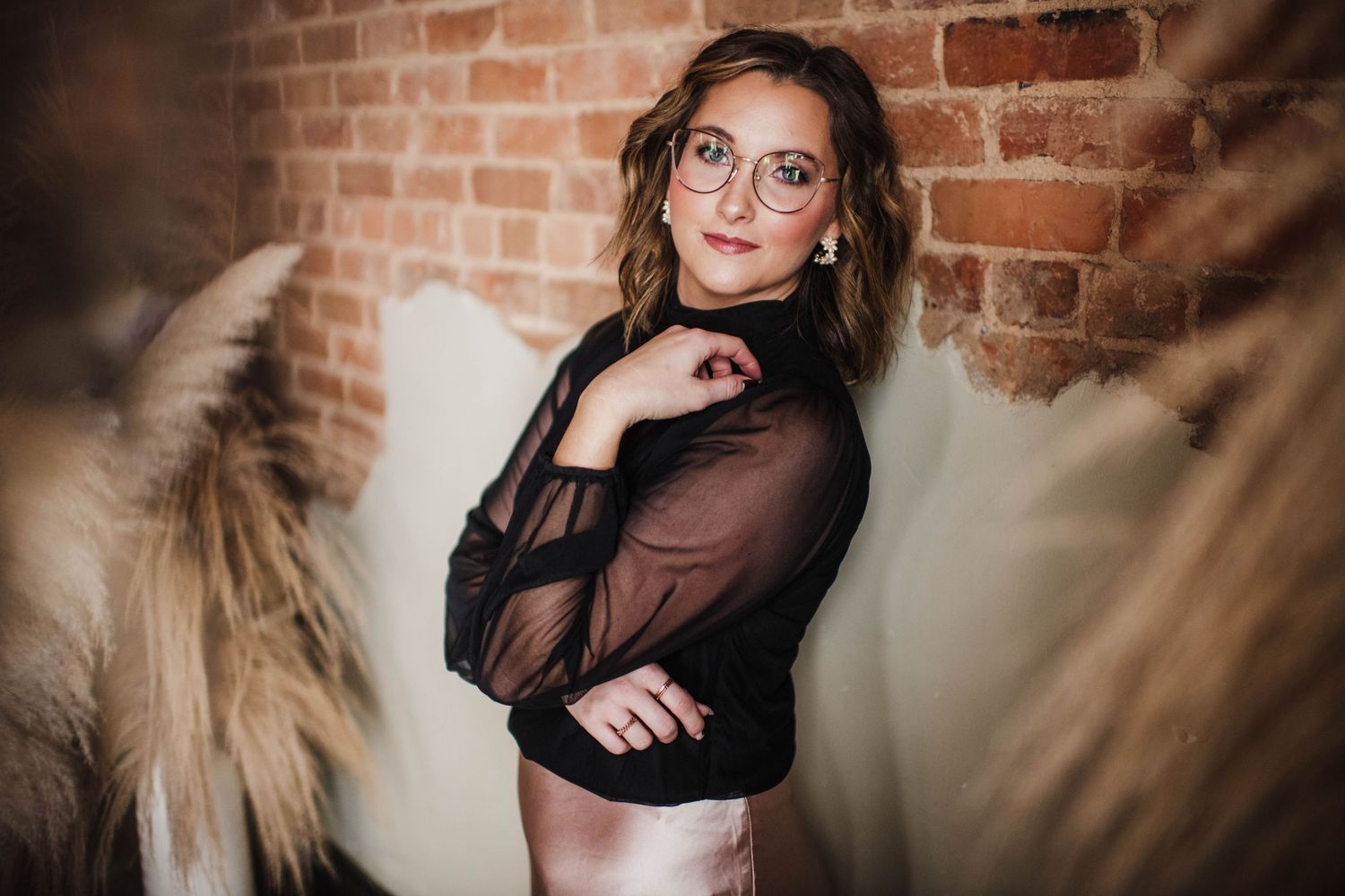 Artistic portrait session against exposed brick wall featuring casual professional style.