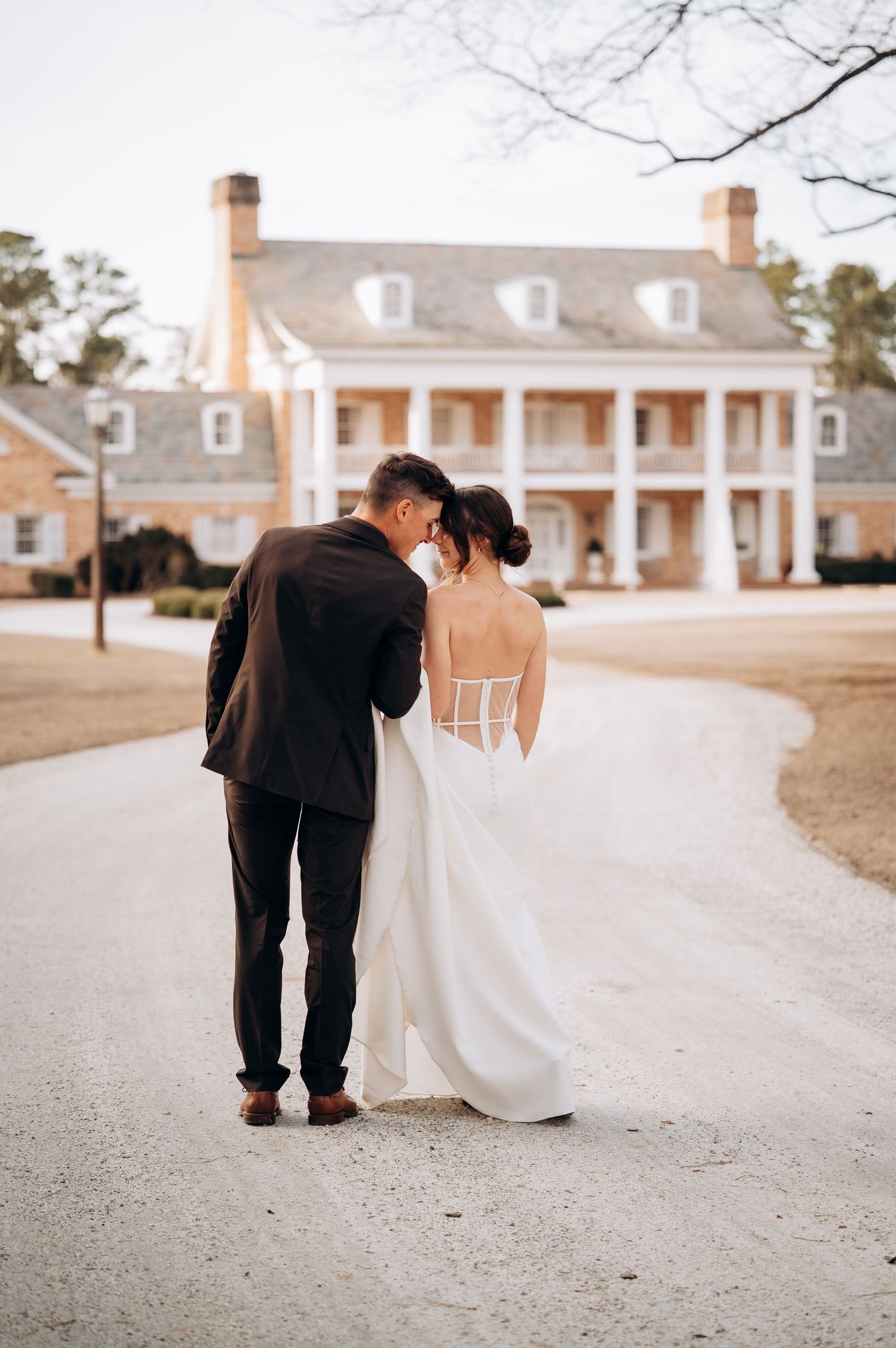 Elegant wedding photos taken outside a classic Southern colonial style mansion with brick details.