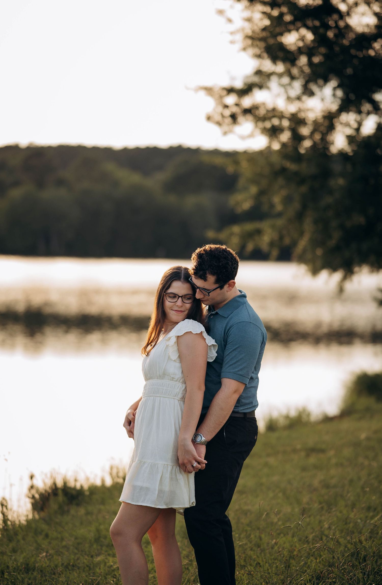 A romantic lakeside photoshoot captures an intimate moment between a couple at dusk.
