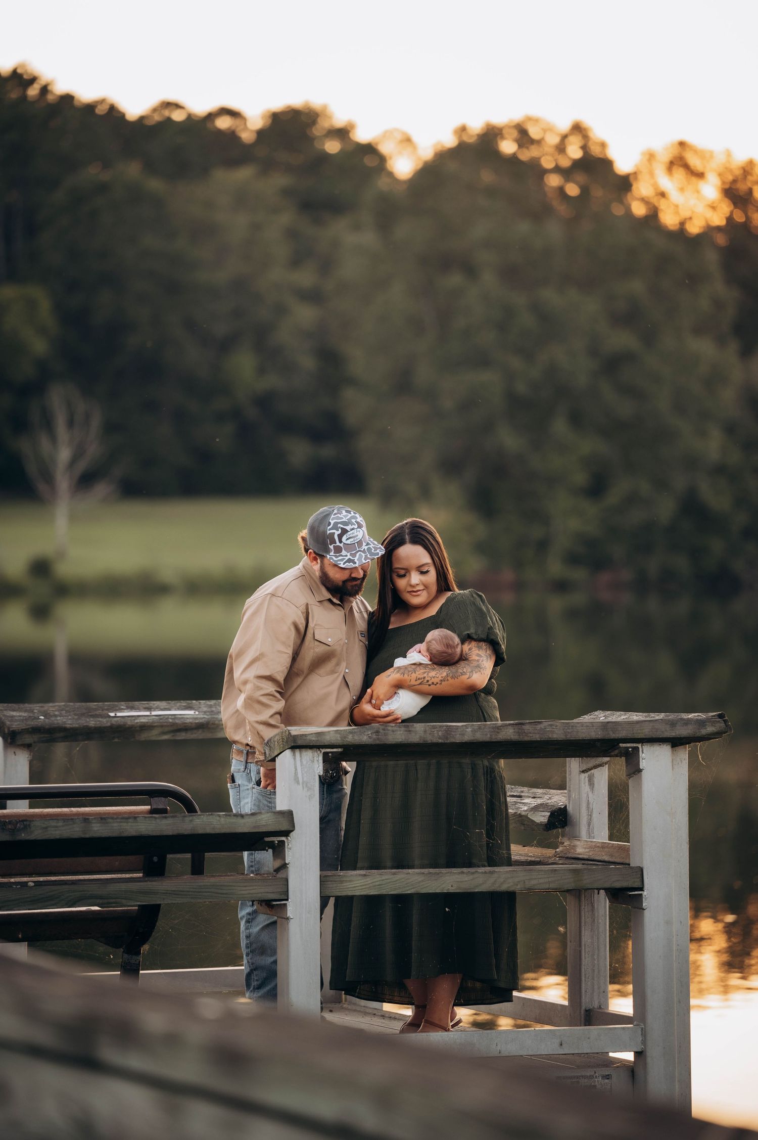 Family sharing tender moment on wooden dock at sunset.
