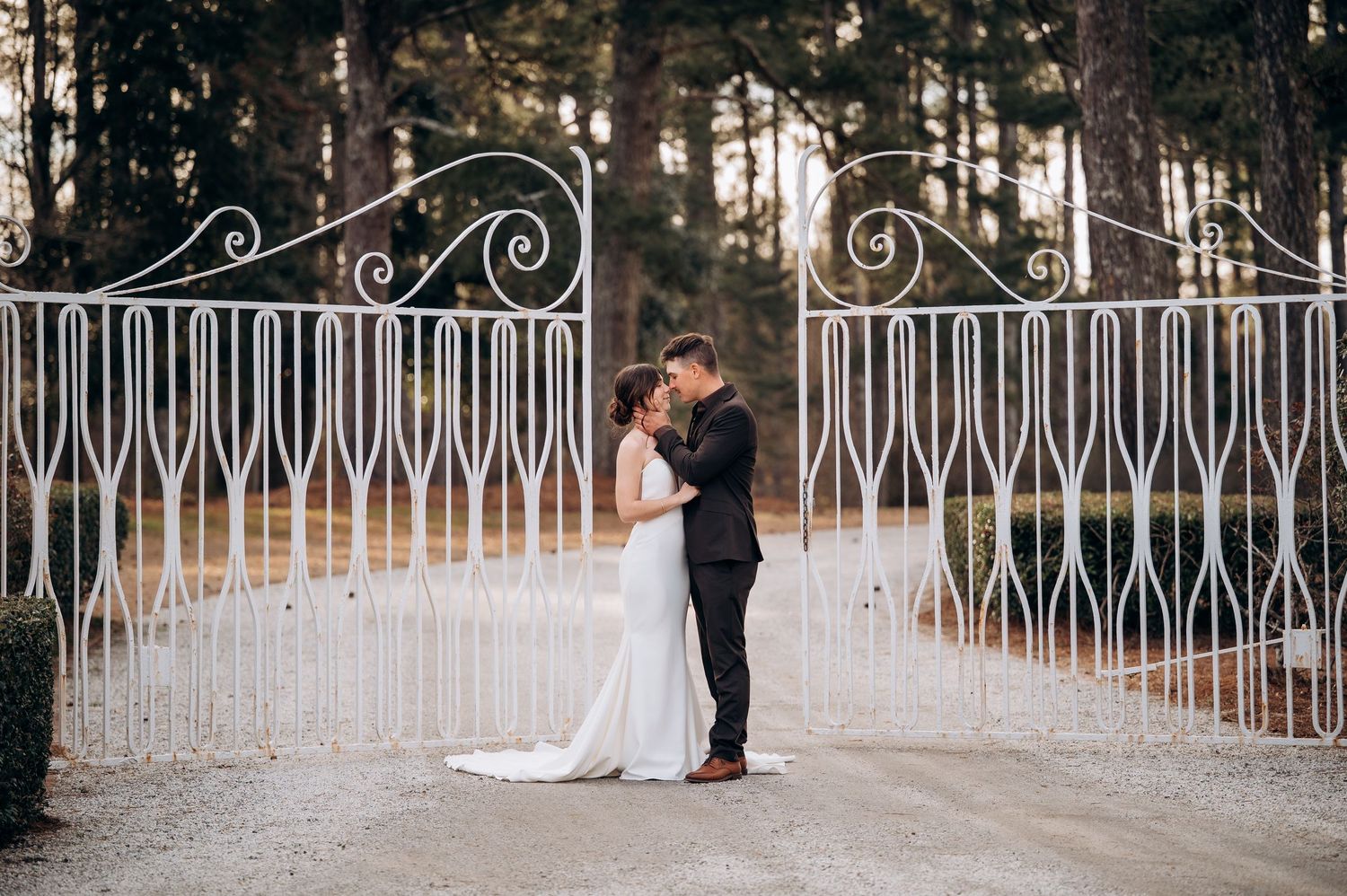Romantic wedding photos captured along a decorative white railing with pine trees in background.