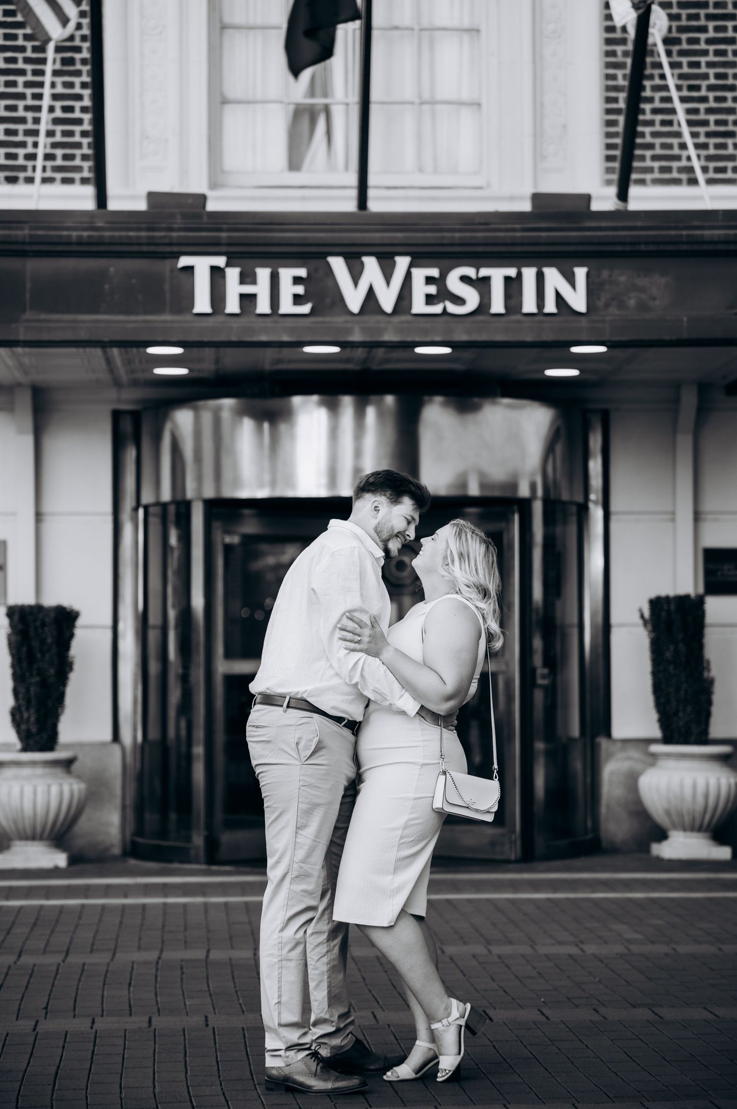Black and white photo of a couple embracing outside The Westin hotel entrance.