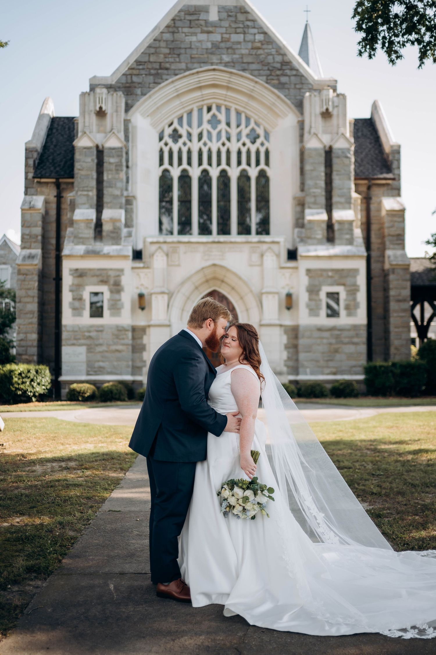 Romantic wedding photos captured on church grounds with classic architecture in background.