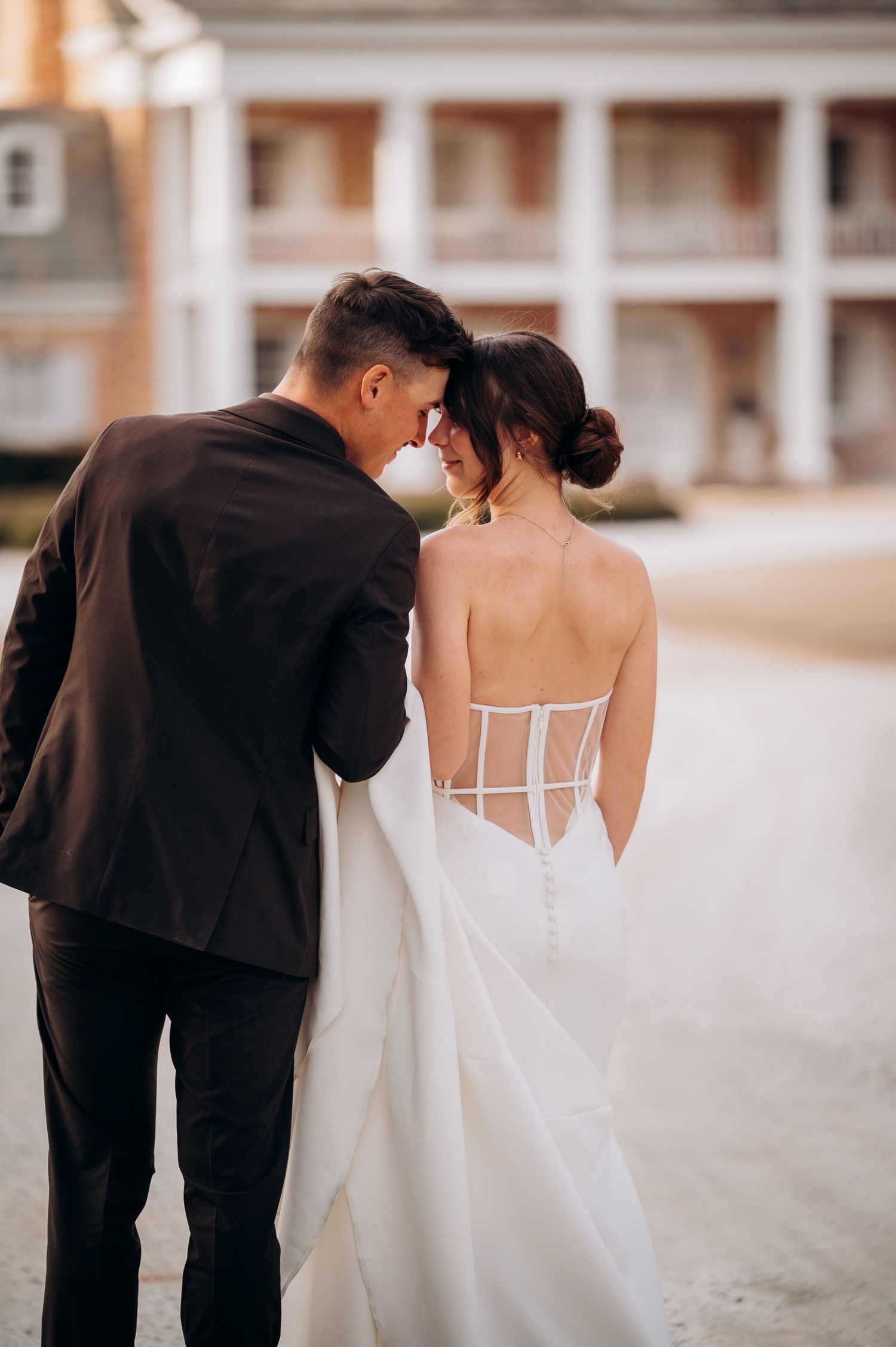 A close-up view of a couple in wedding attire showing the bride's detailed back dress design.