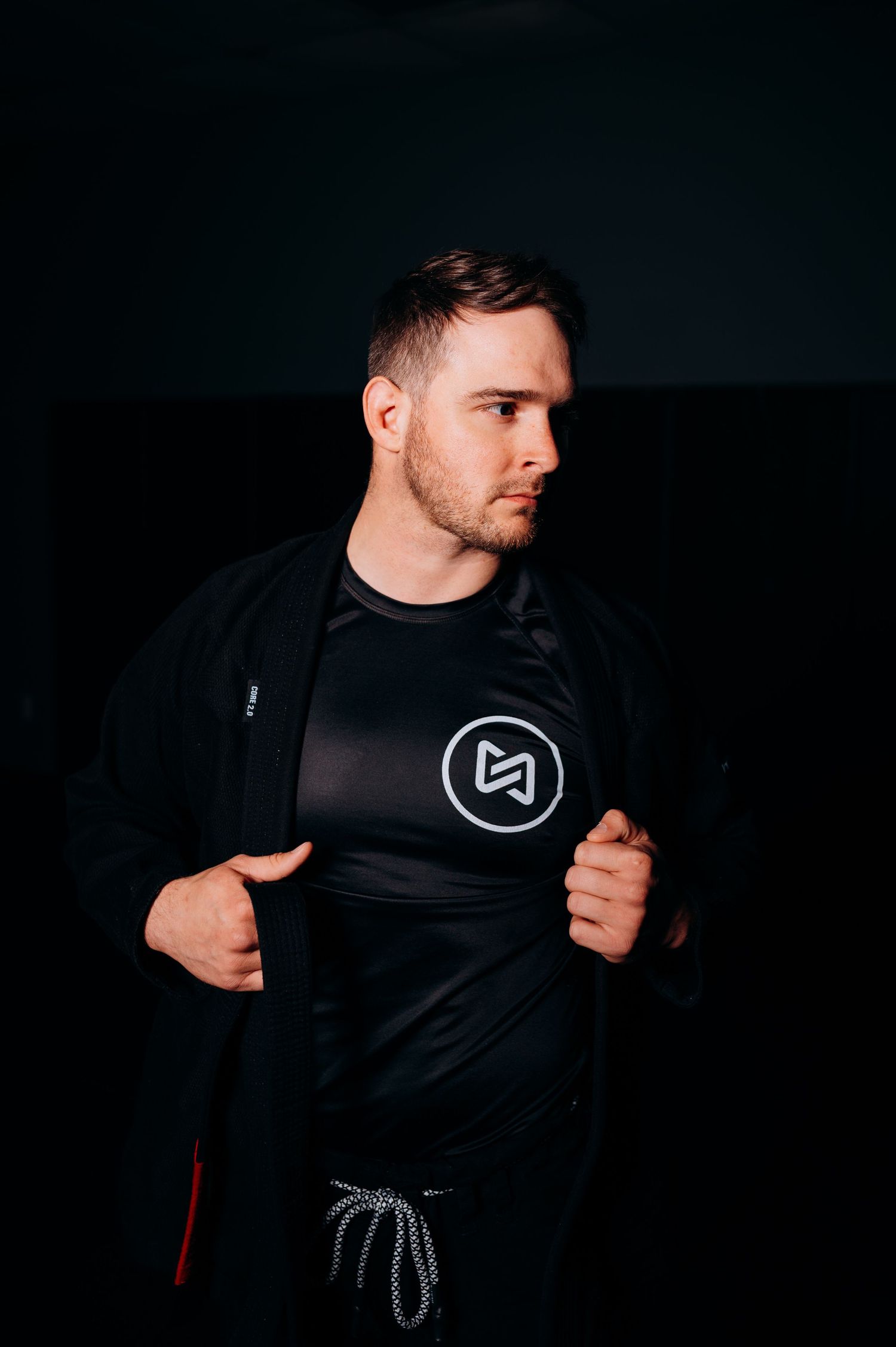 Athletic figure in dark sportswear with logo performing dynamic movement in low-light setting.