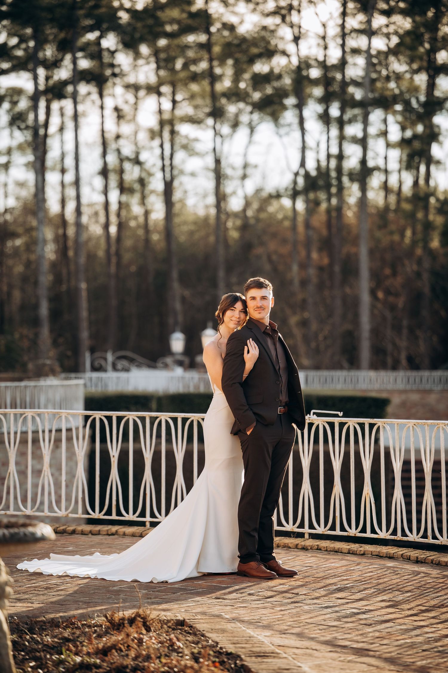 Newlyweds share tender moments on an outdoor terrace with pine forest backdrop.