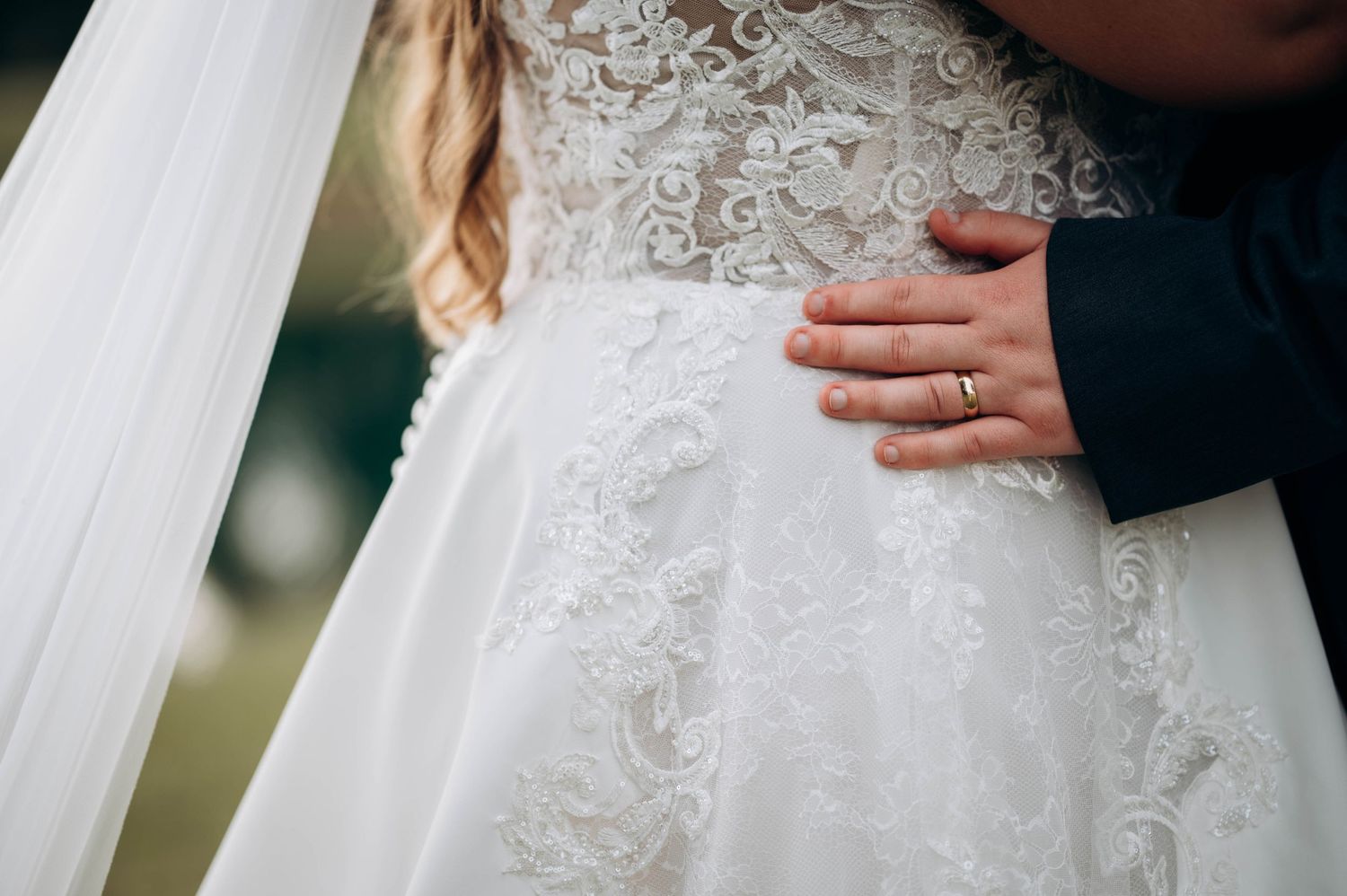 Detail shot of intricate lace pattern on white wedding dress.
