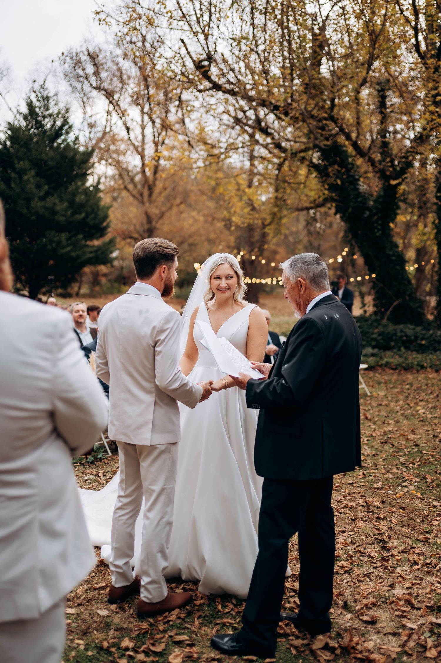 Wedding party walking through fallen autumn leaves at outdoor ceremony.