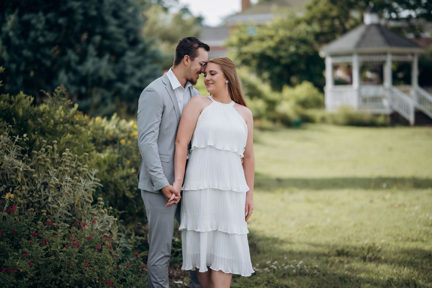 A couple shares a romantic moment in a garden setting with yellow flowers and greenery.