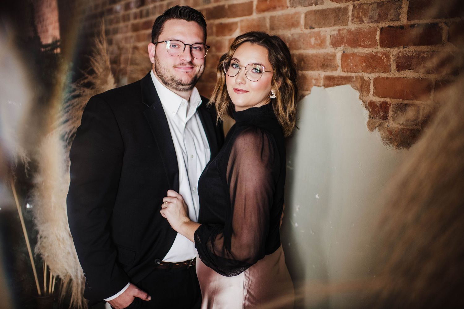 Moody portrait session against exposed brick wall with dramatic lighting.