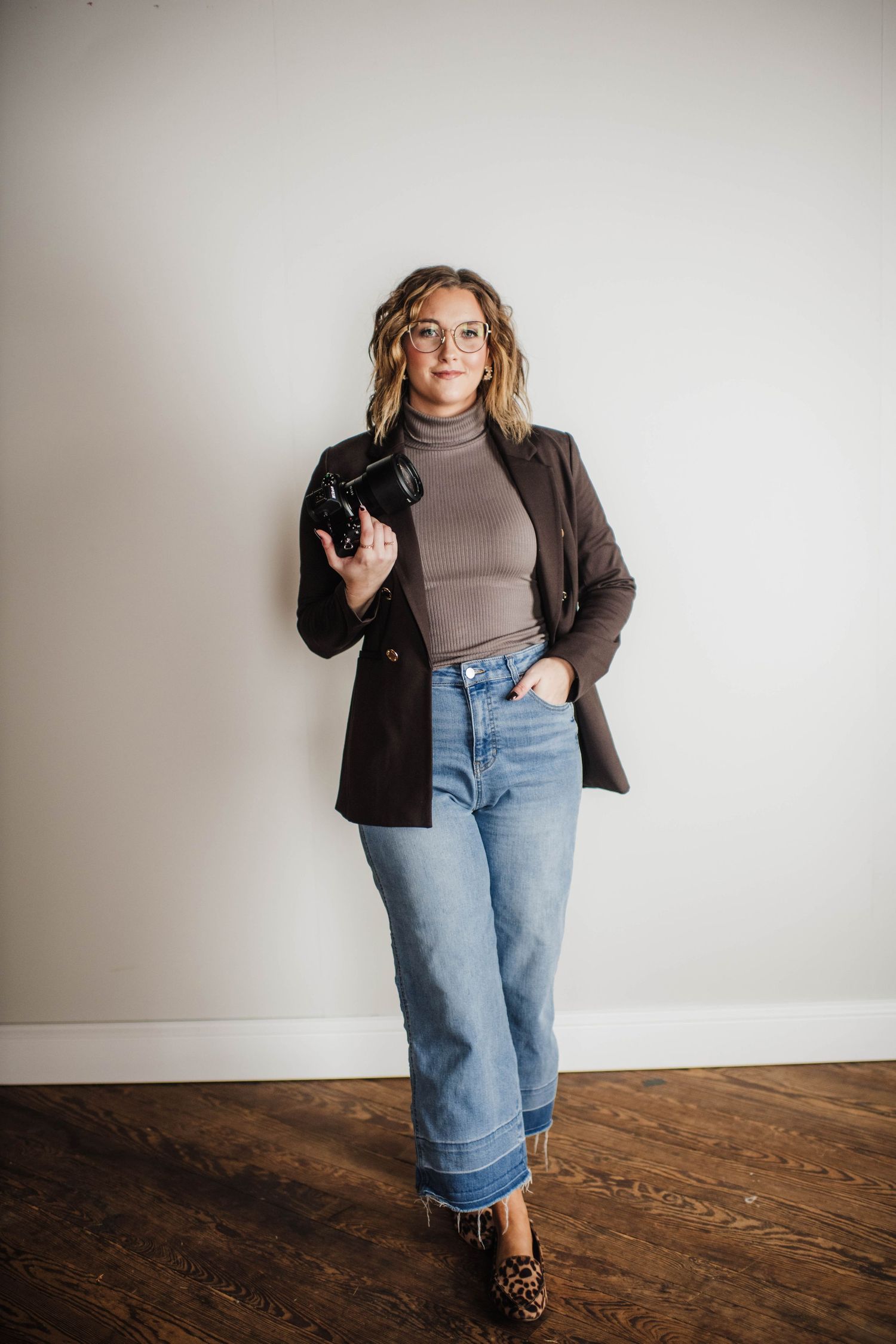 Fashion-forward photographer in brown turtleneck and jeans showing professional poses.