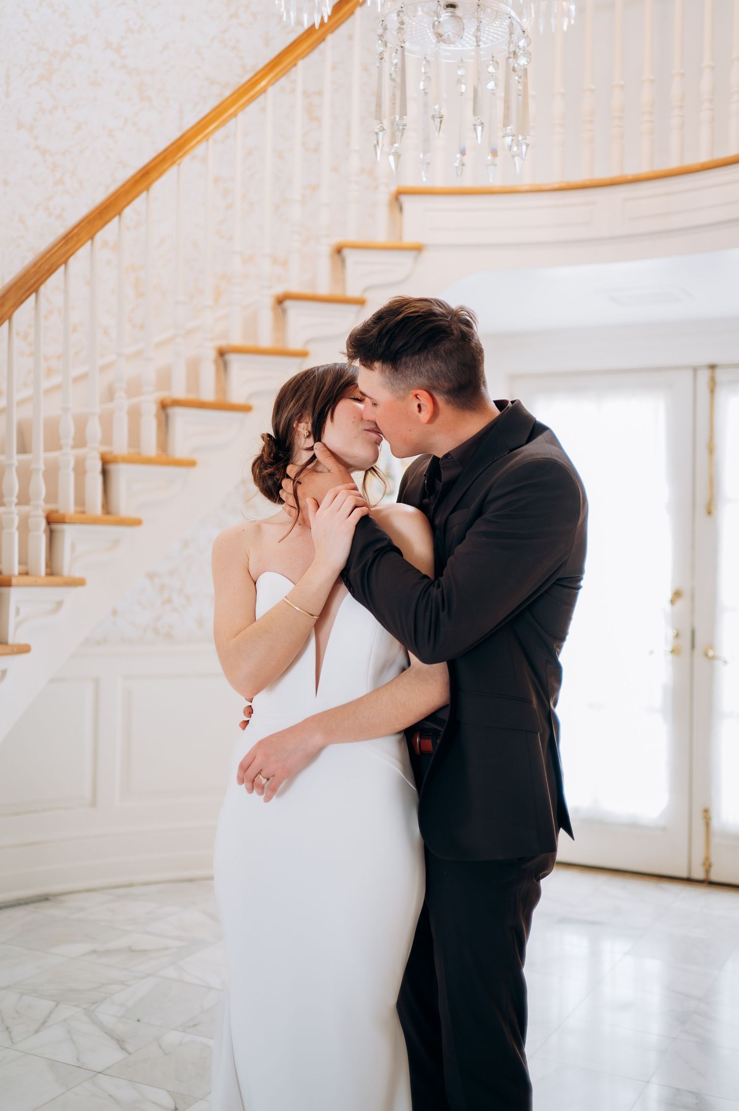 Wedding couple sharing an intimate first look moment in an elegant white room.
