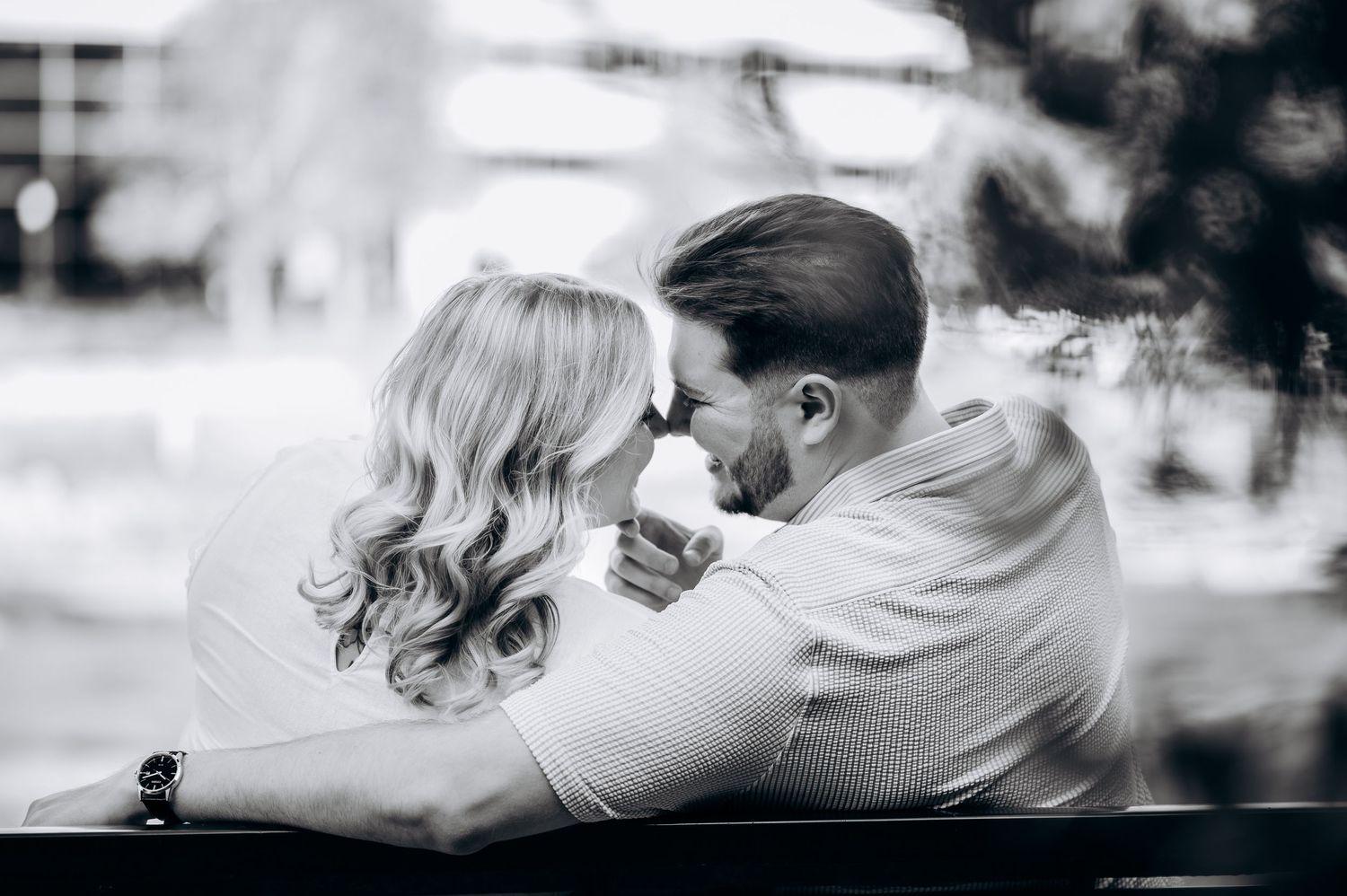 Romantic black and white photo of couple leaning in for a kiss during outdoor engagement session.