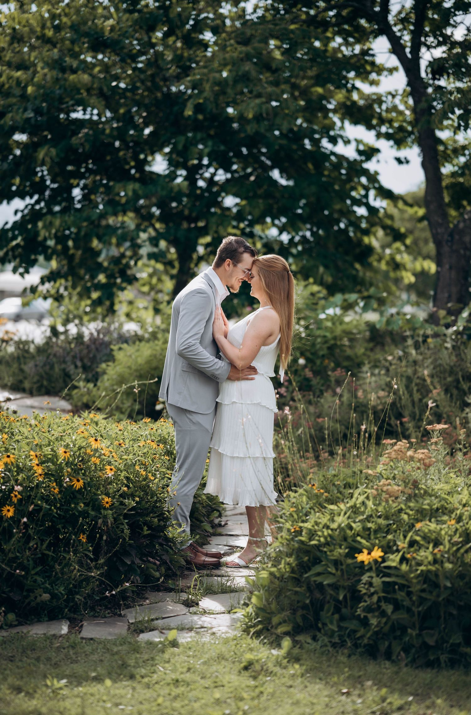 A romantic photoshoot in a lush garden with blooming yellow flowers and trees.