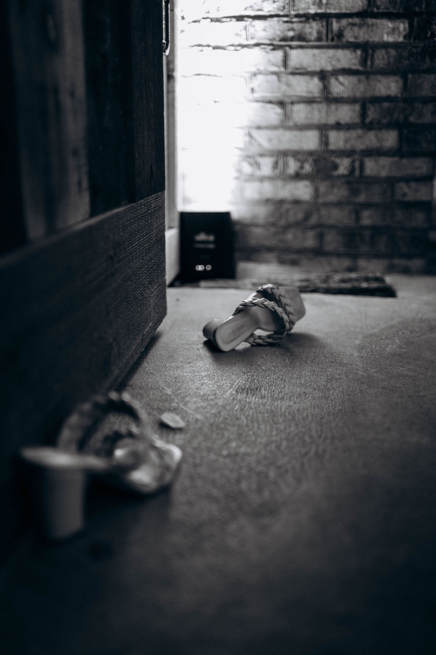 Artistic black and white detail shot of shoes against a brick wall.