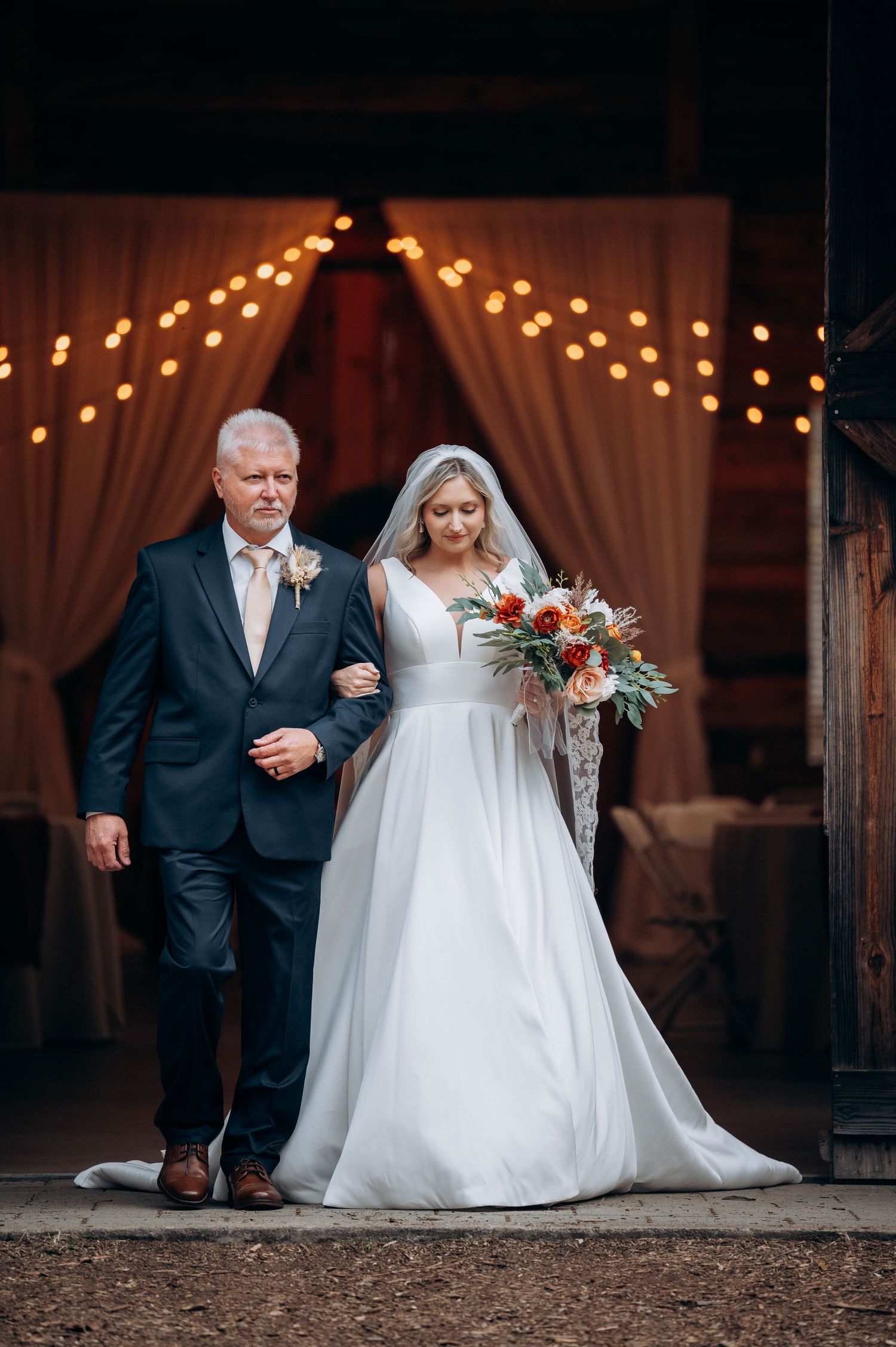 Wedding ceremony under string lights with bride in white dress walking down aisle.