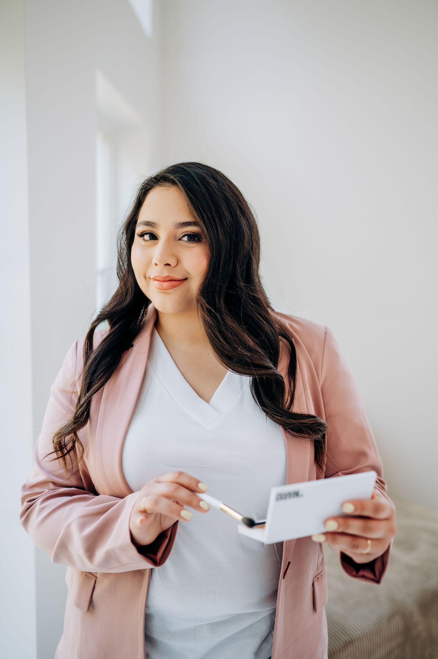 Professional lifestyle photo series of someone in a pink blazer and white top reading documents against a white wall.
