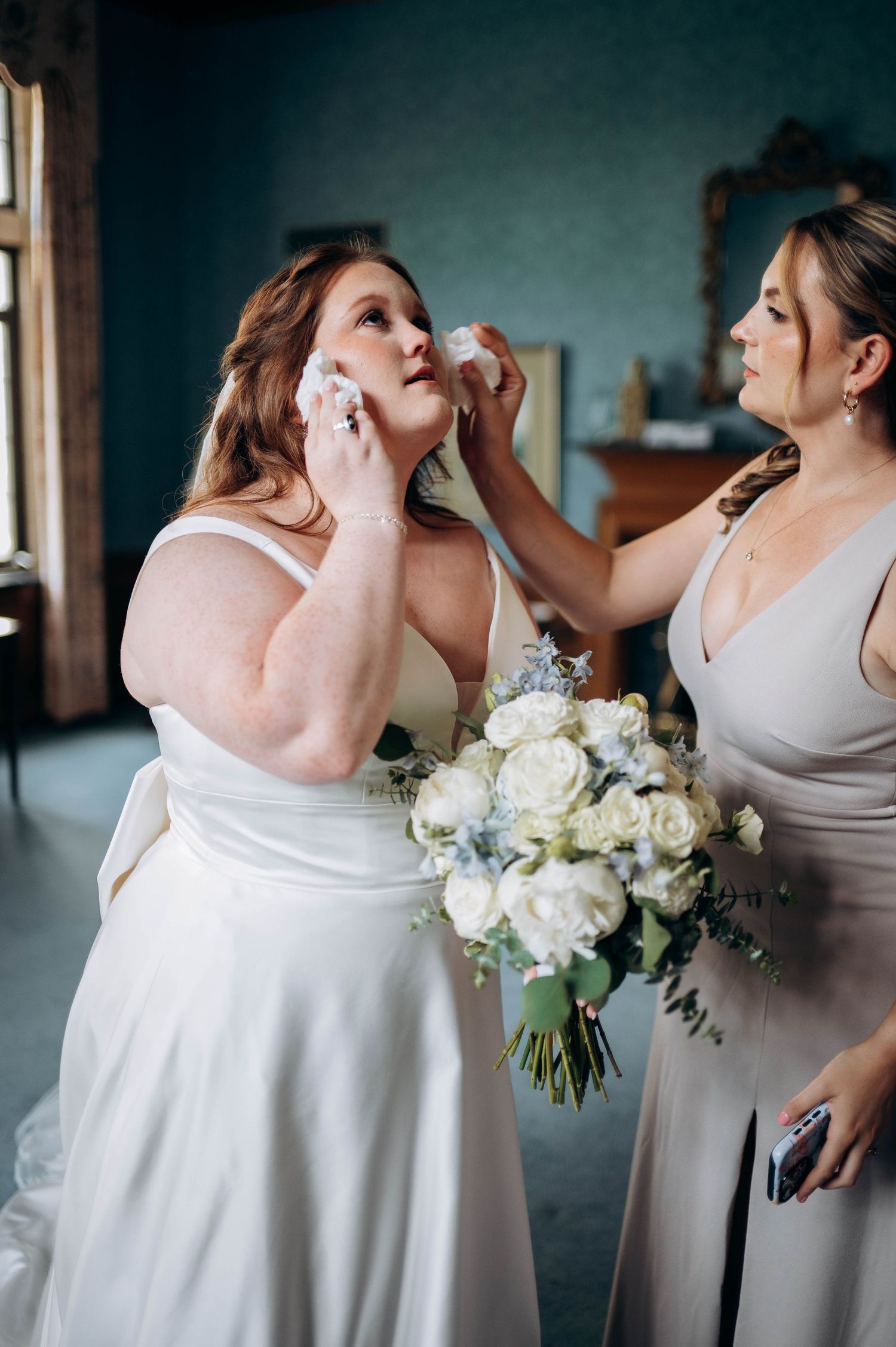 Bridesmaids in light colored dresses hold elegant white floral bouquets during a wedding celebration.