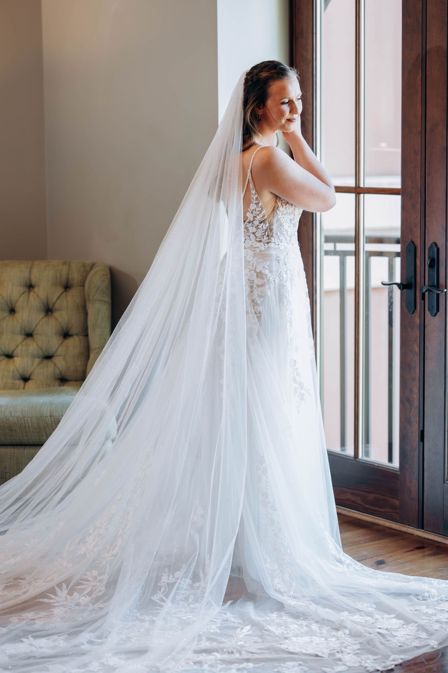 Dramatic bridal portrait showcasing lace wedding gown with cathedral length veil indoors.