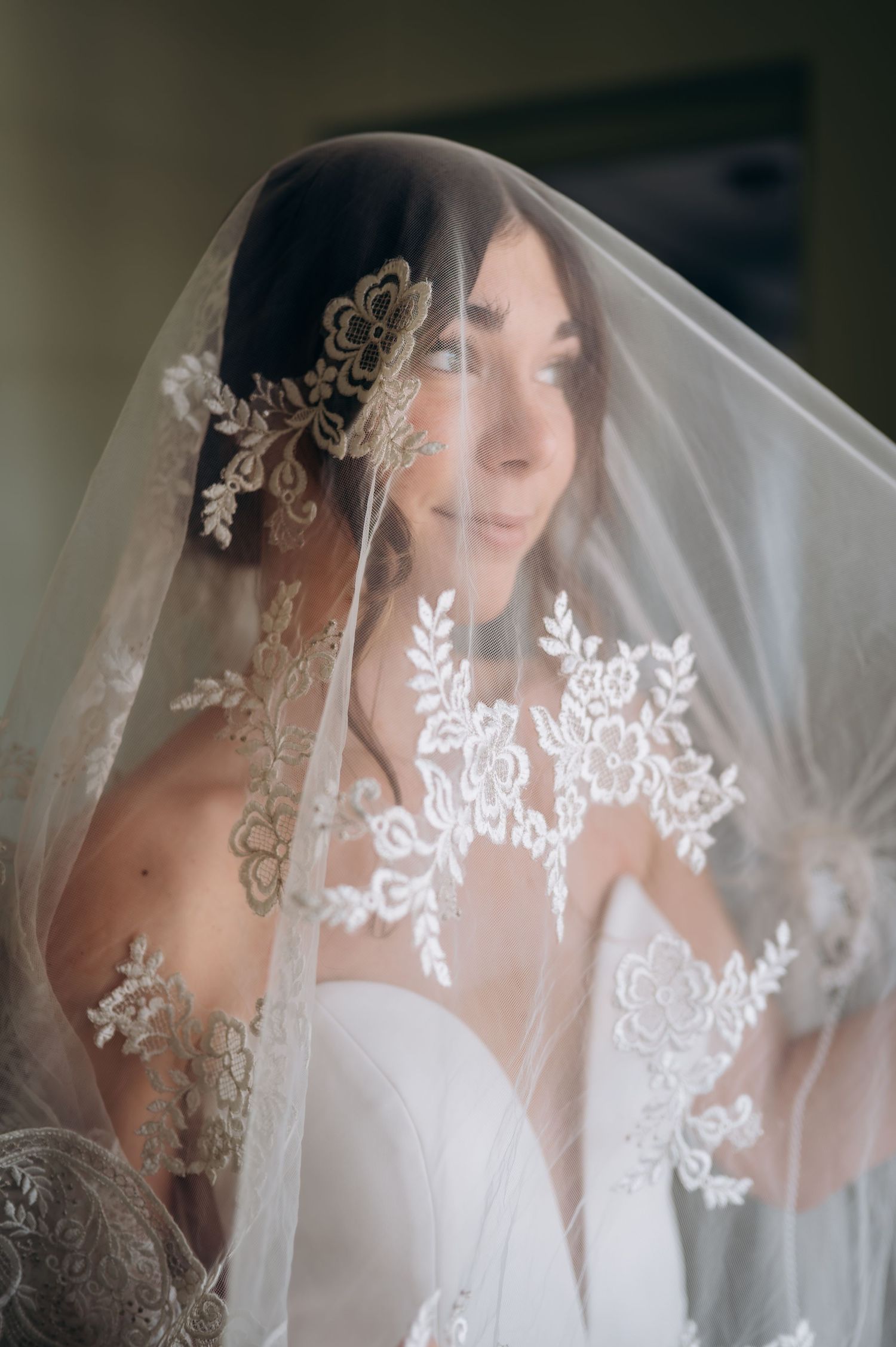Bride in a lace-trimmed veil with floral headpiece wearing a strapless wedding gown.