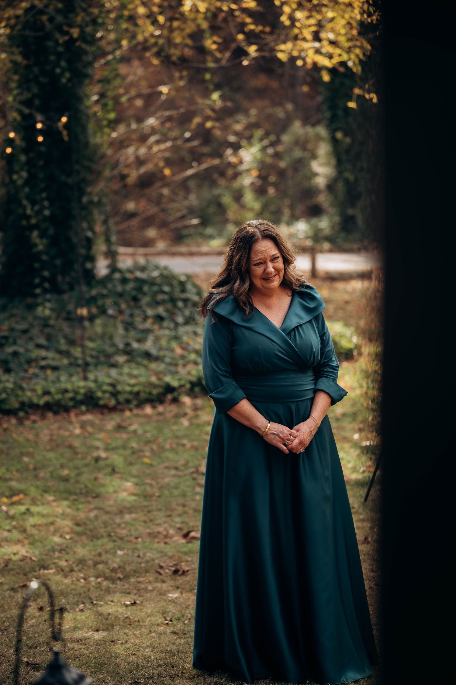 Person in a navy blue formal dress standing in an autumn garden setting.