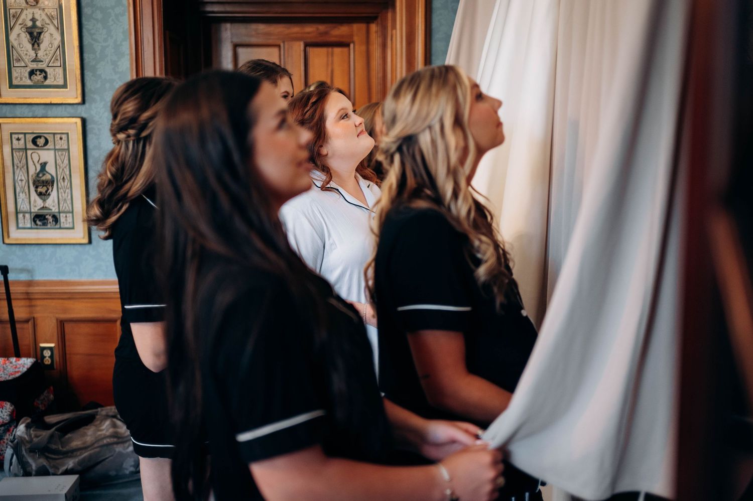 Behind-the-scenes moment of wedding preparations with attendants in matching outfits.