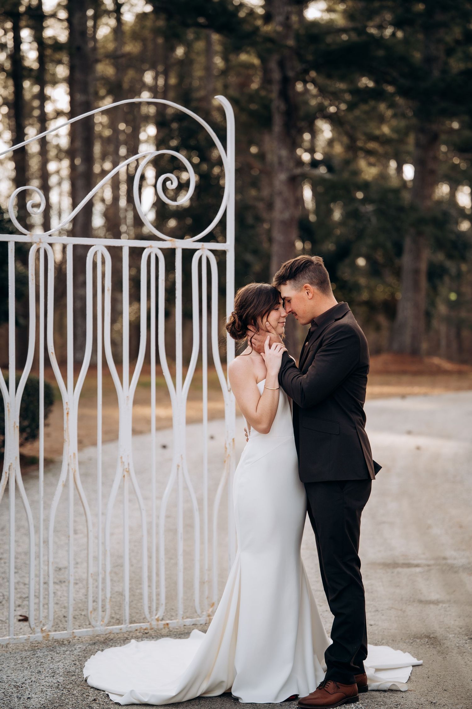A romantic wedding photo against white decorative fencing outdoors.