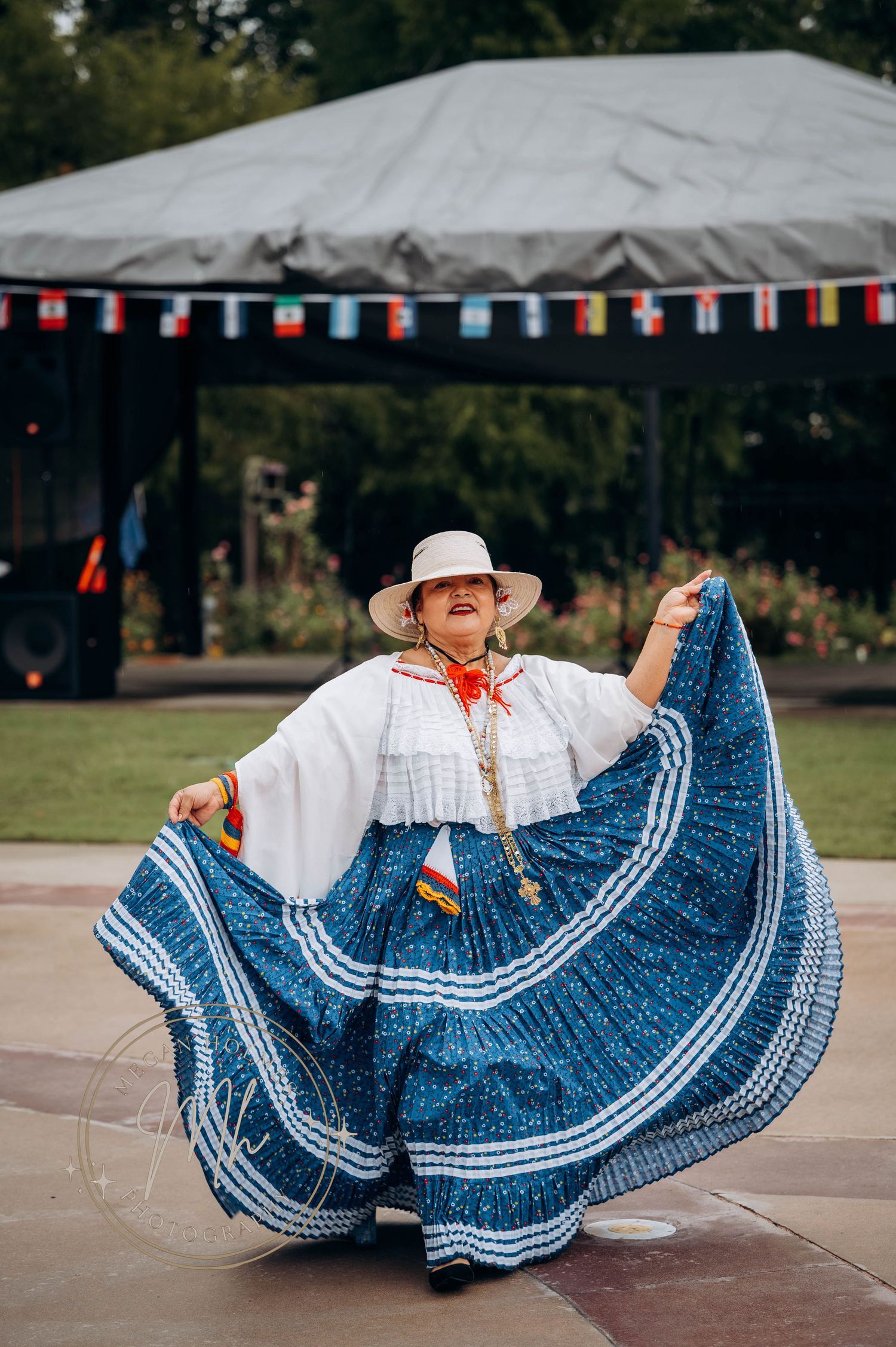 Traditional dancer twirls in a flowing blue and white patterned dress under outdoor tent.