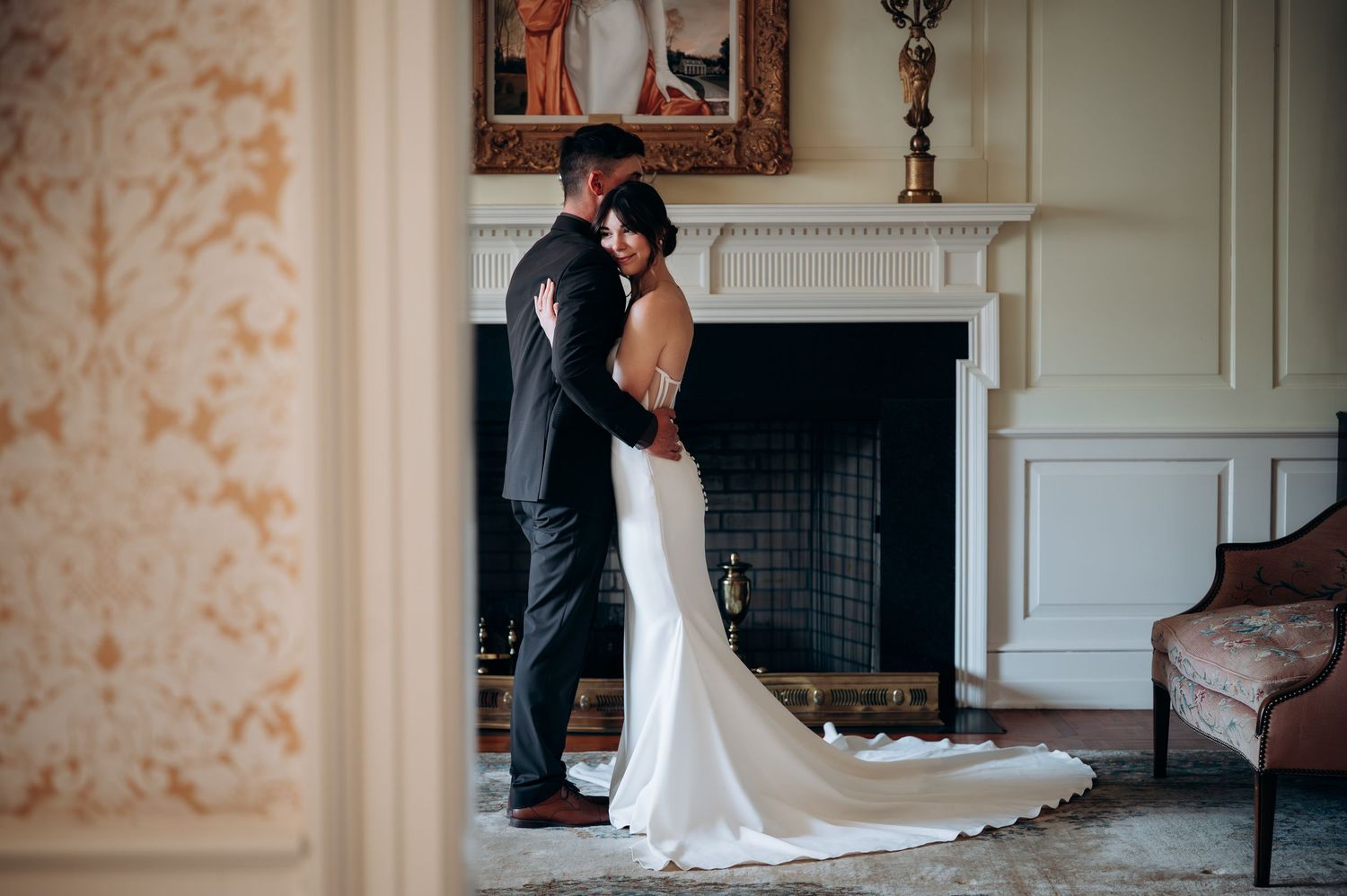 Wedding couple photographed in elegant room with vintage wallpaper and classic decor.