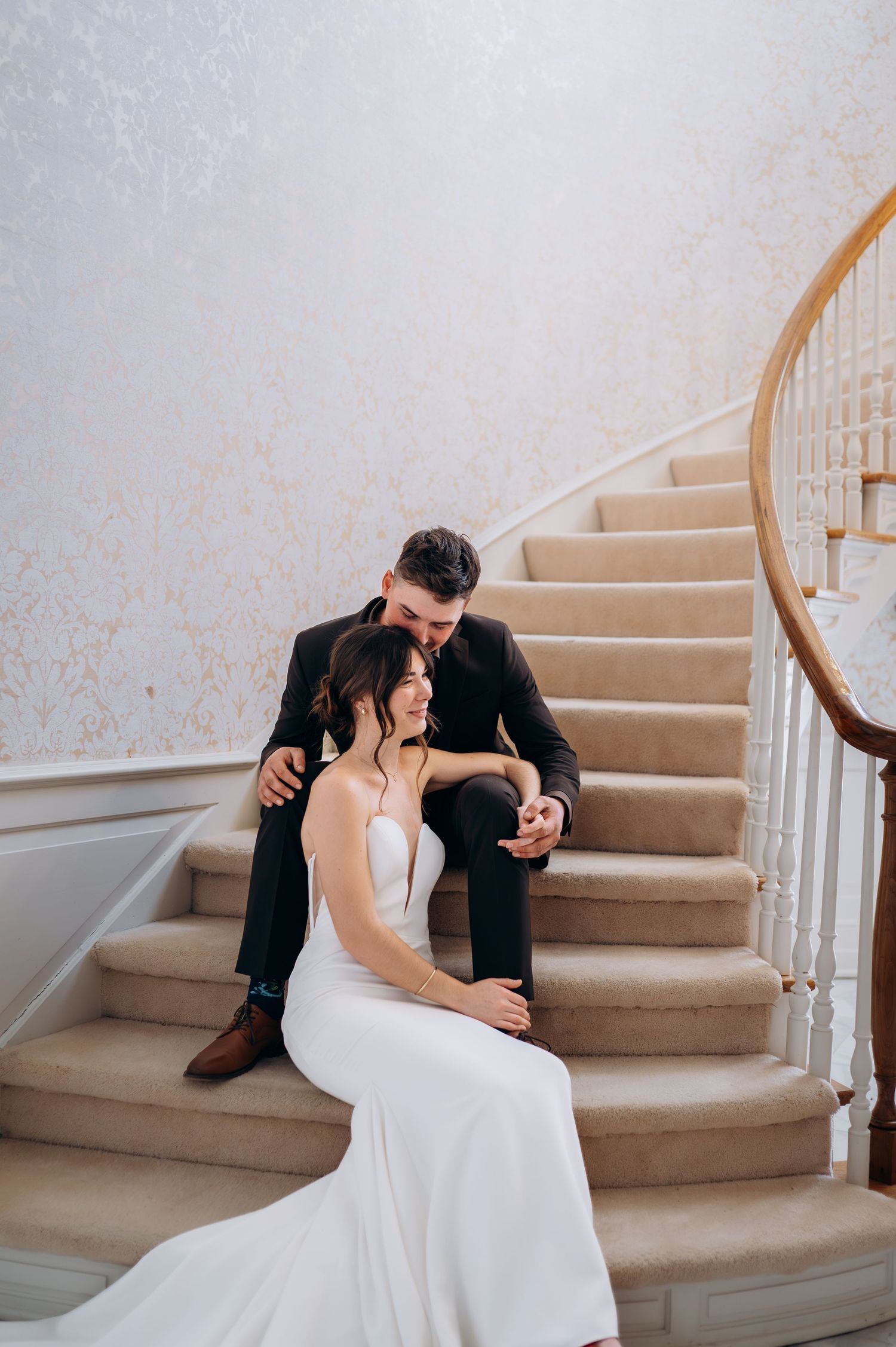 Bride and groom sitting together on elegant carpeted staircase in a grand venue.