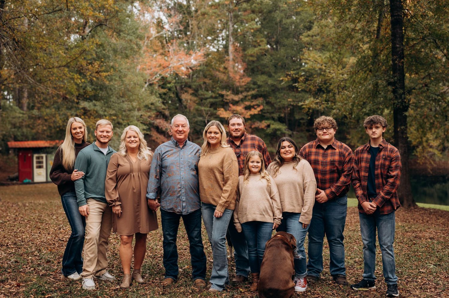 Large family group photo with coordinated earth-tone outfits in autumn setting.