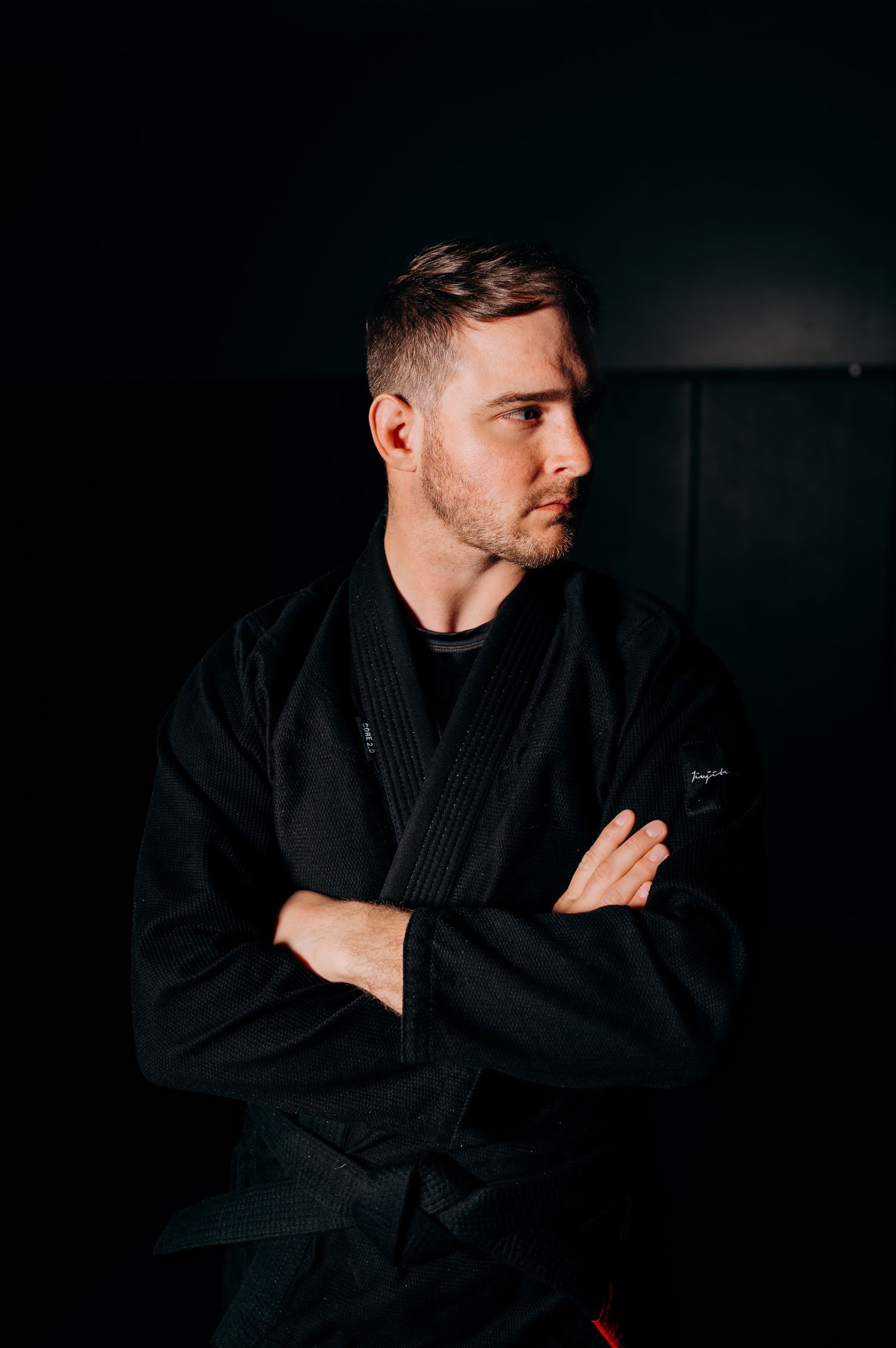 Side profile shots of person wearing black martial arts gi in dramatic studio lighting.