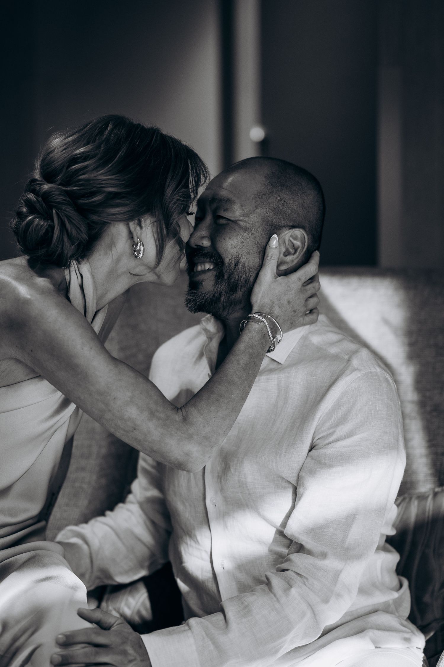 Black and white photo of a laughing couple sharing an intimate moment together.