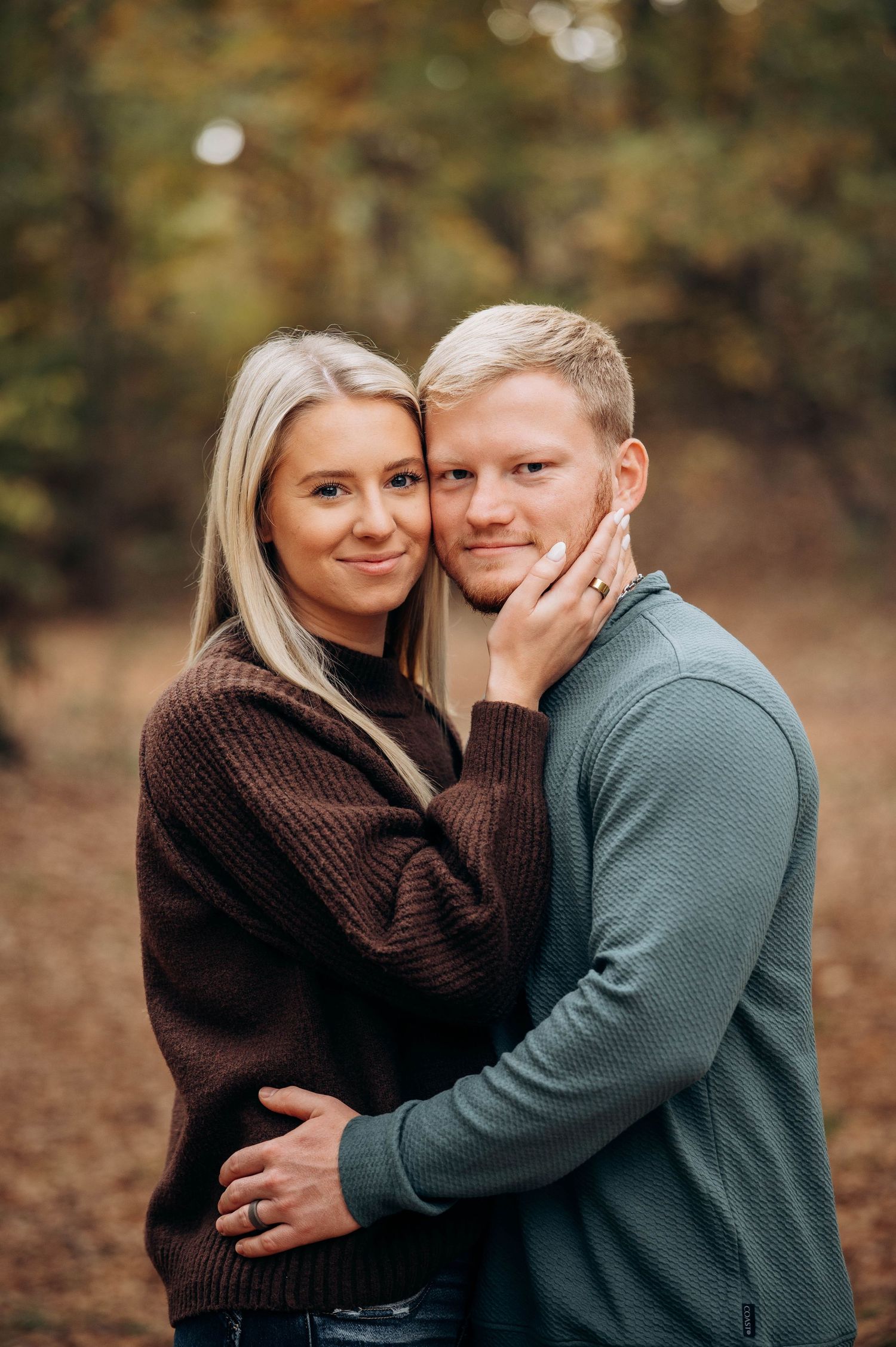 A couple in cozy sweaters shares an intimate moment during a fall photoshoot.