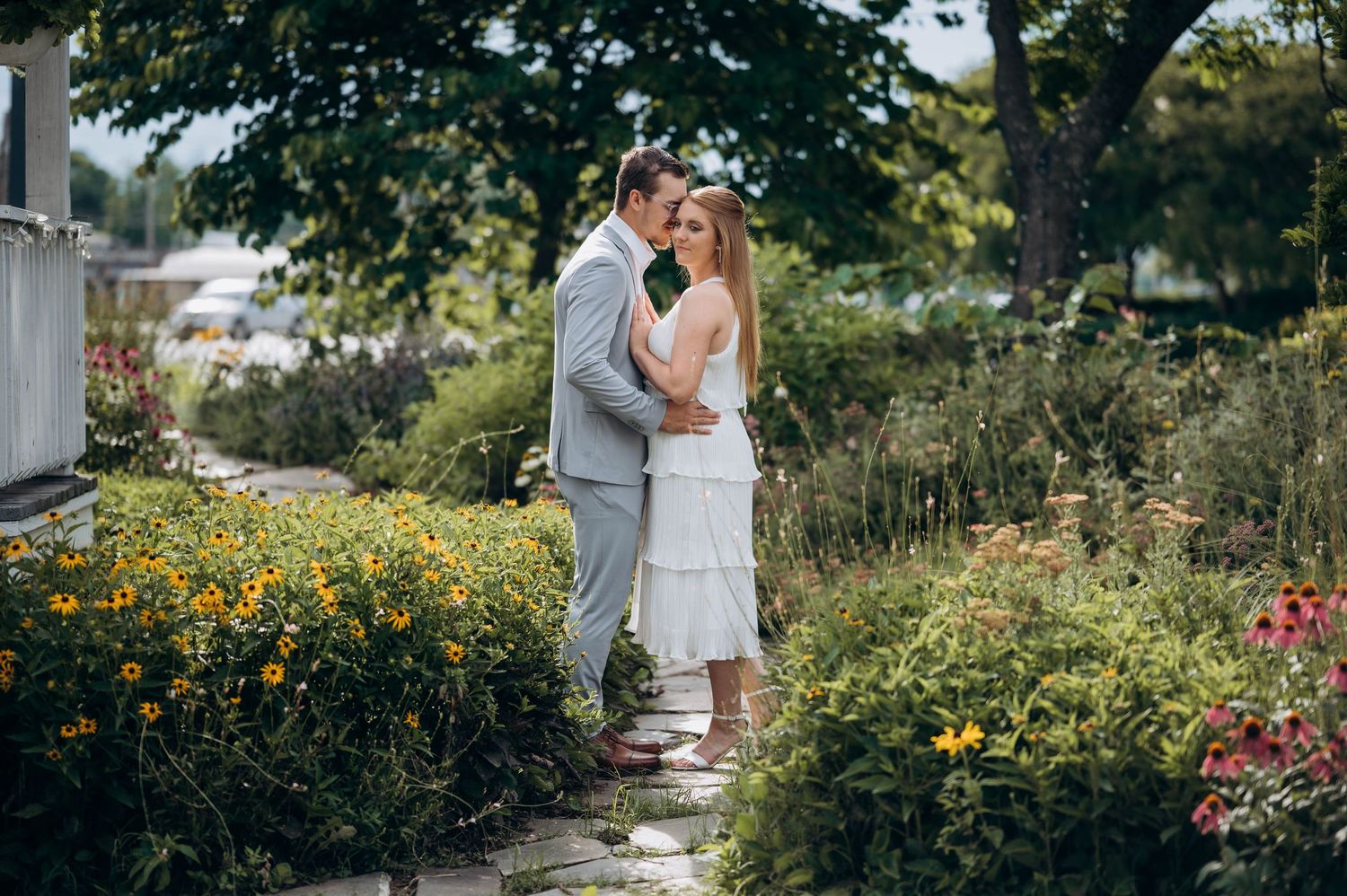 A couple embraces in a beautiful garden setting with yellow wildflowers in bloom.