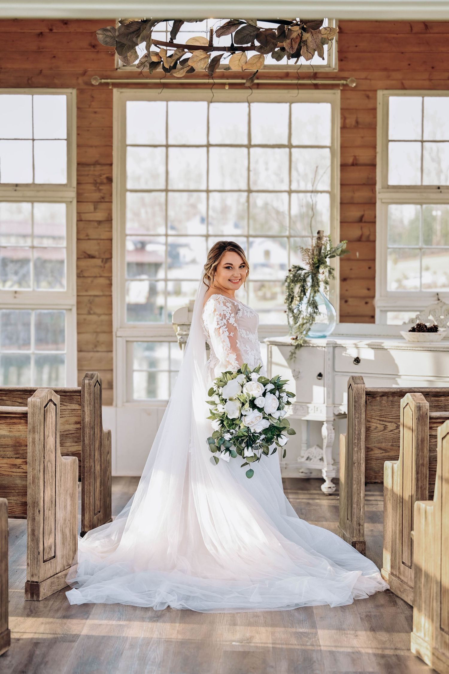 Stunning bridal portrait in rustic wooden chapel with natural light streaming through windows.