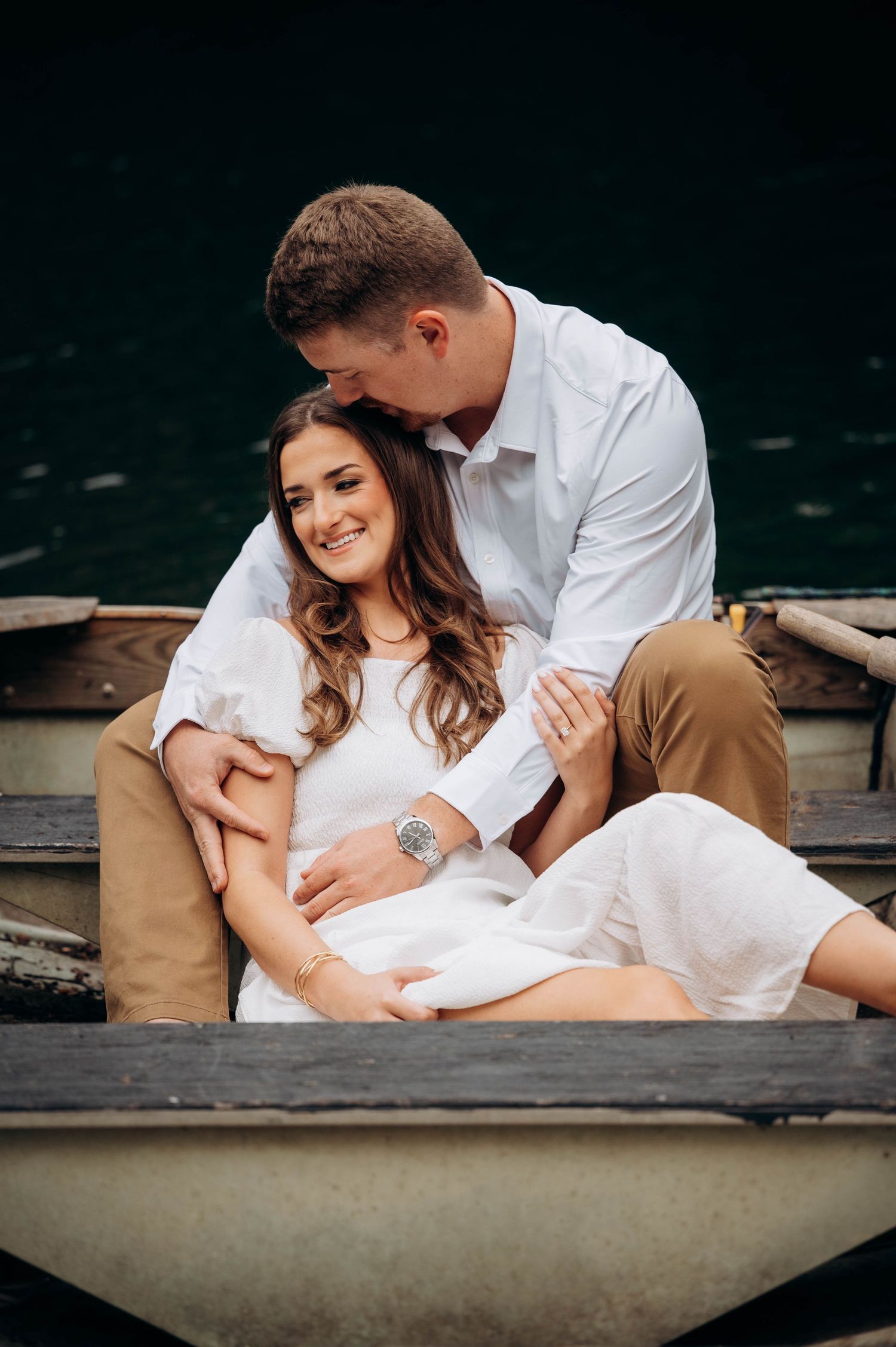 Tender moments captured between a couple in white clothing relaxing in a small boat.
