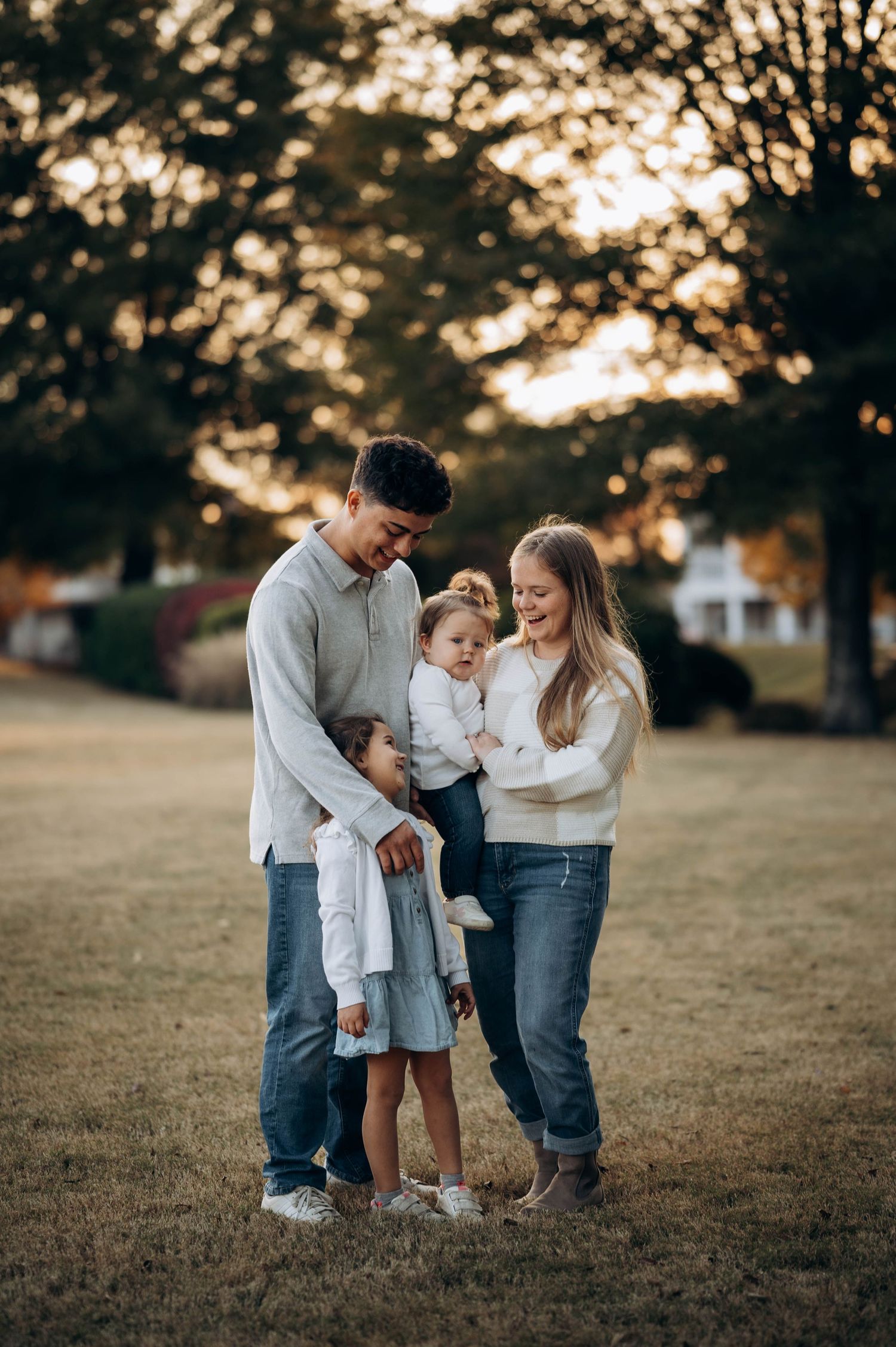 A family shares a tender moment together at sunset in a grassy field.