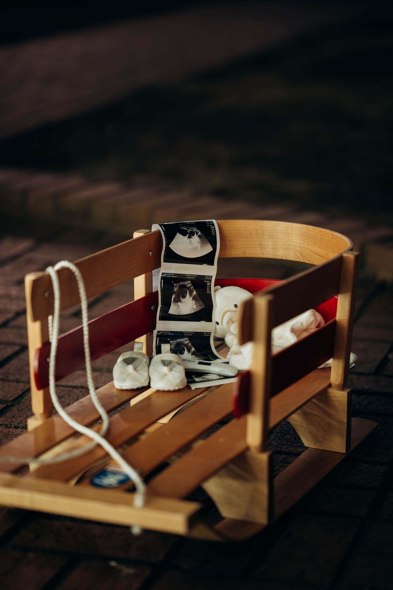 Wooden sled with ultrasound photos and baby booties for Christmas pregnancy announcement.