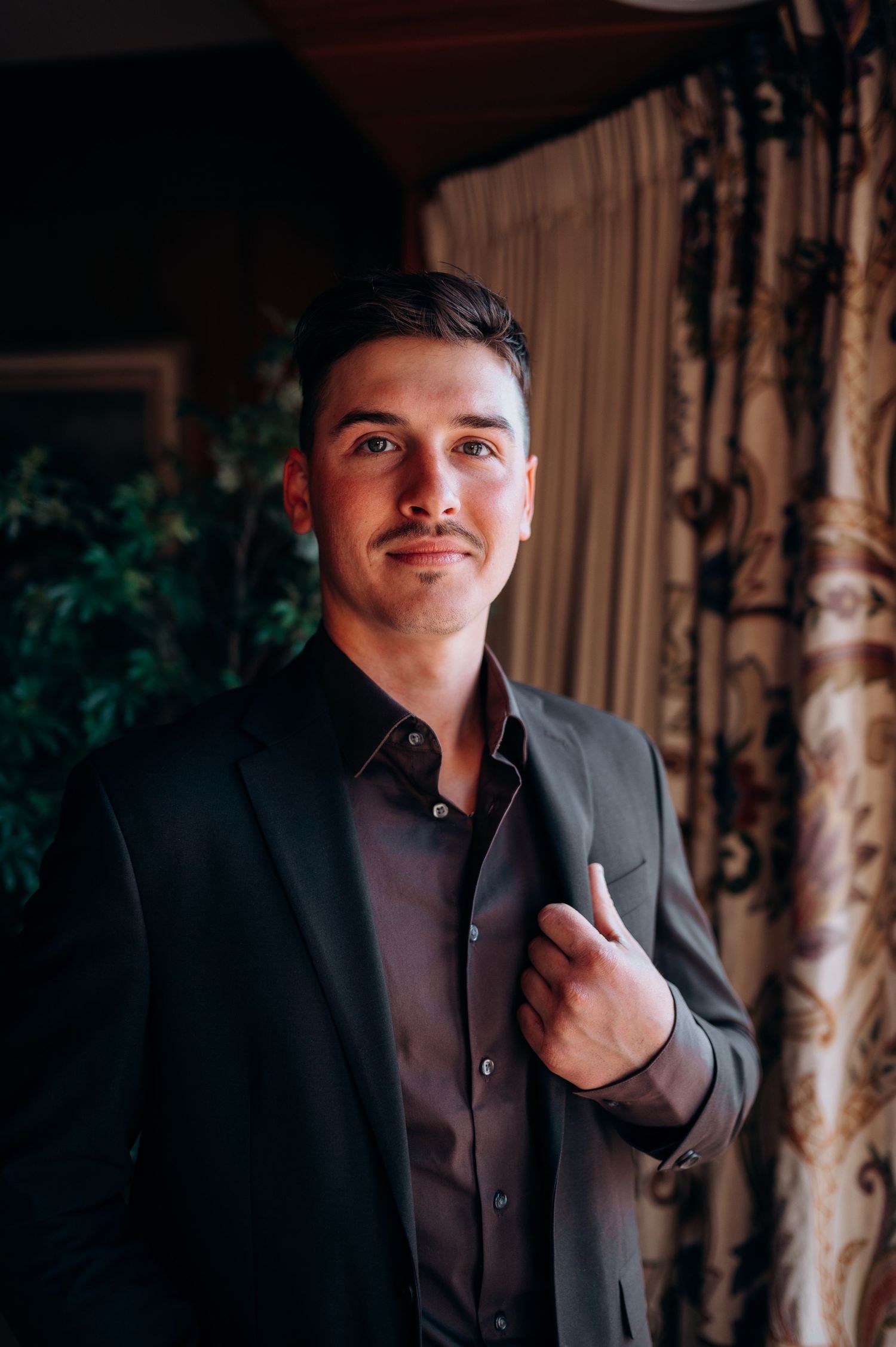 Professional portrait series showing a black suit against an elegant interior background.