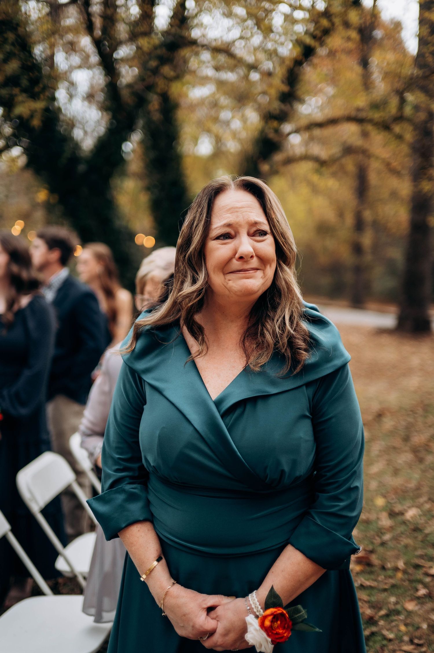 Person in teal wrap dress at an outdoor autumn wedding event.