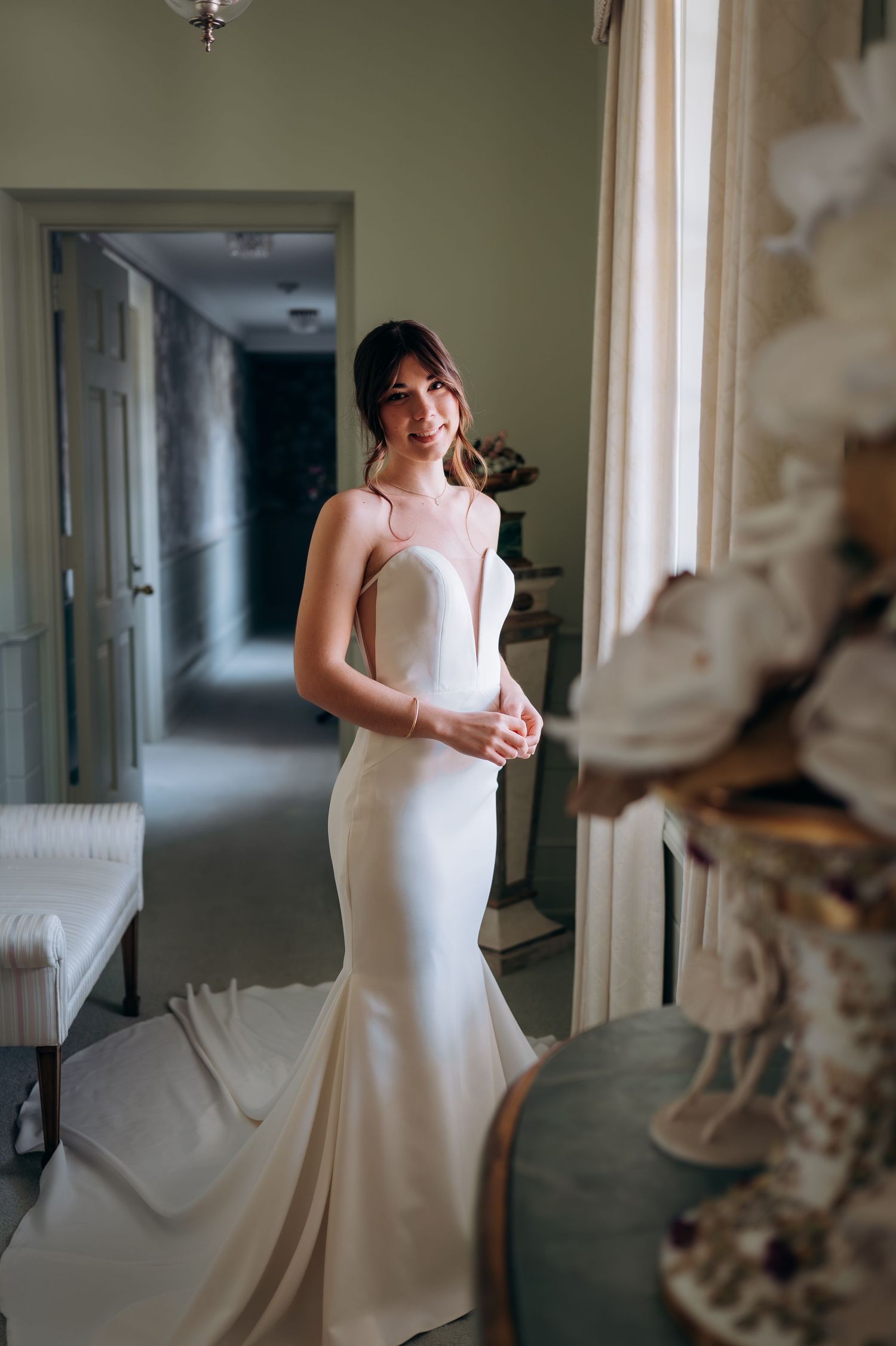 Elegant white mermaid wedding dress with fitted silhouette and sweetheart neckline photographed in a hallway.