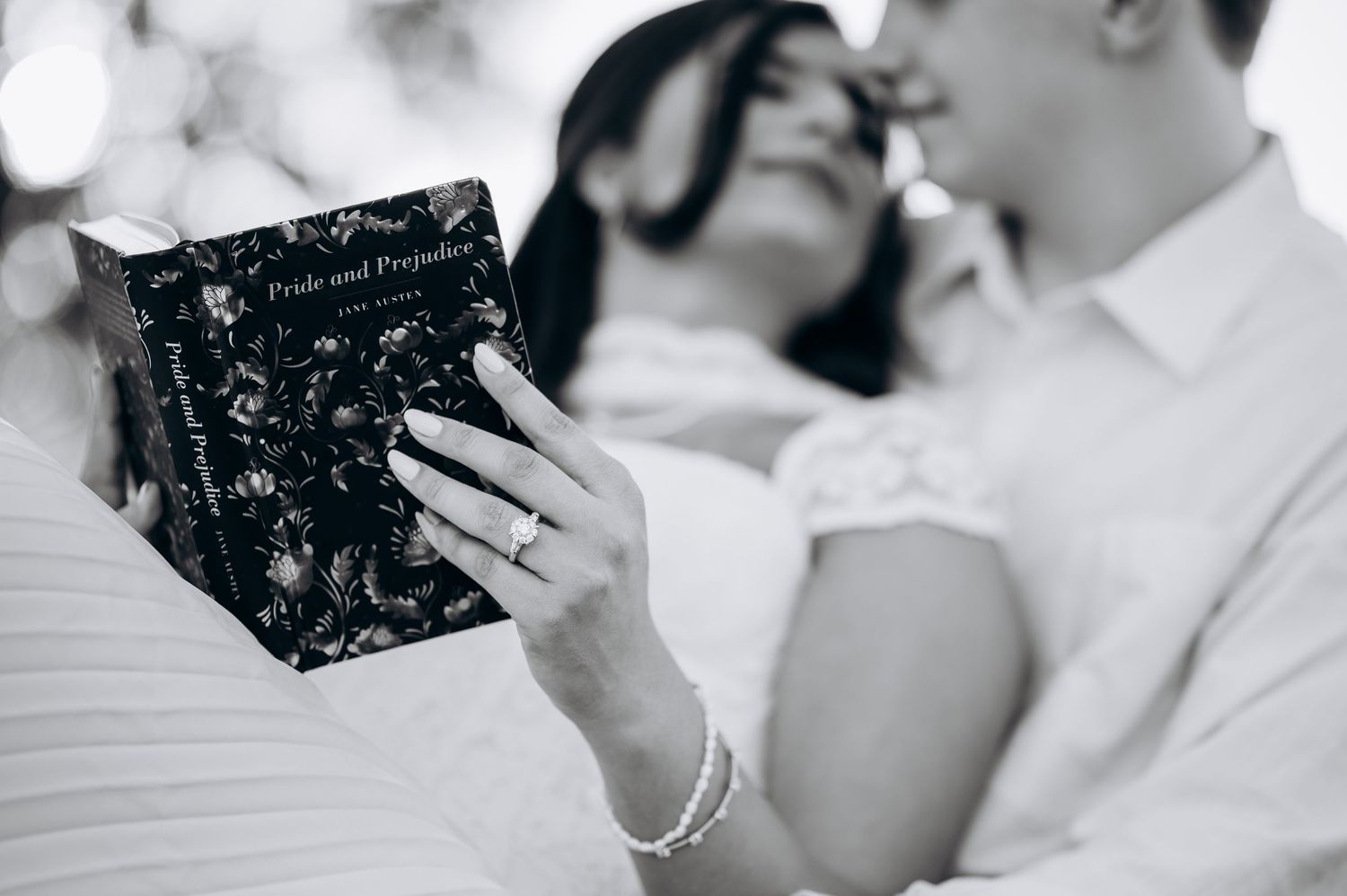 Couple sharing romantic moment with Pride and Prejudice book in black and white engagement photo.