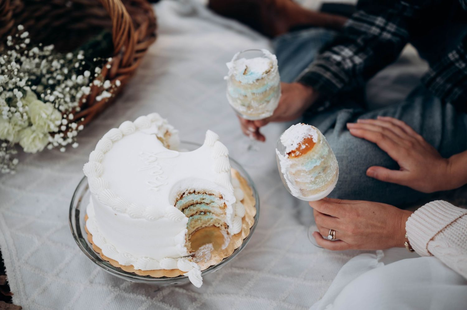 Hands reaching for slices of cake during gender reveal celebration.