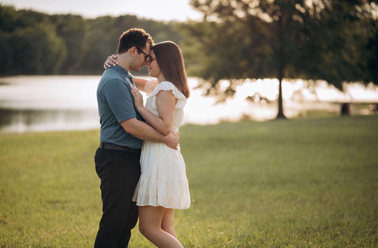 A panoramic view shows a couple's romantic moment by the water during sunset.