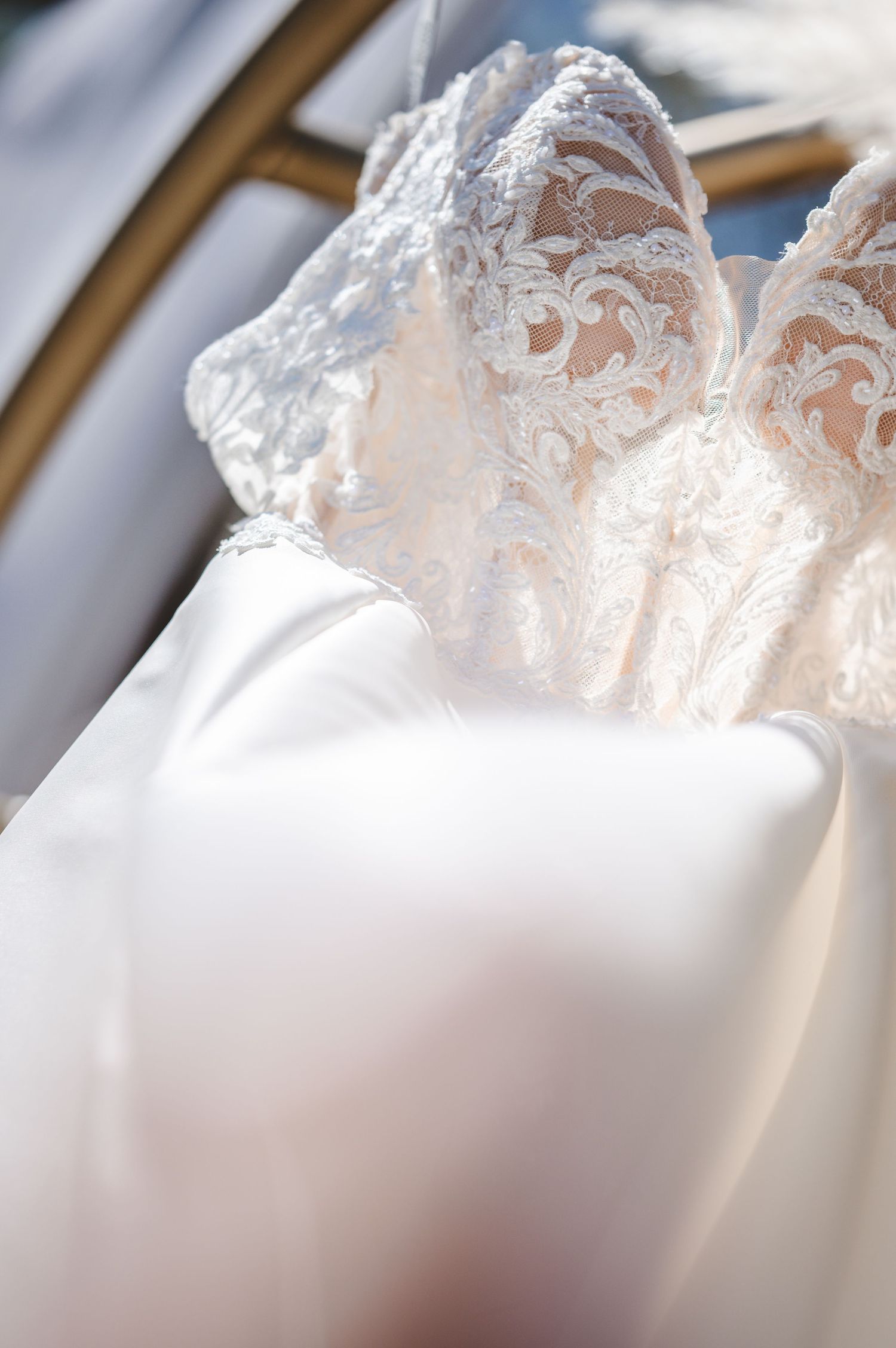 Close-up detail of delicate white lace fabric from a wedding dress in natural light.