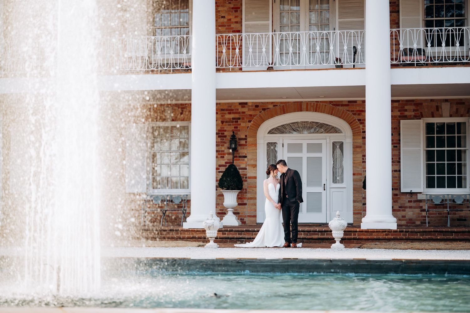 A row of white columns and brick architecture with windows creates a classic colonial-style building facade.