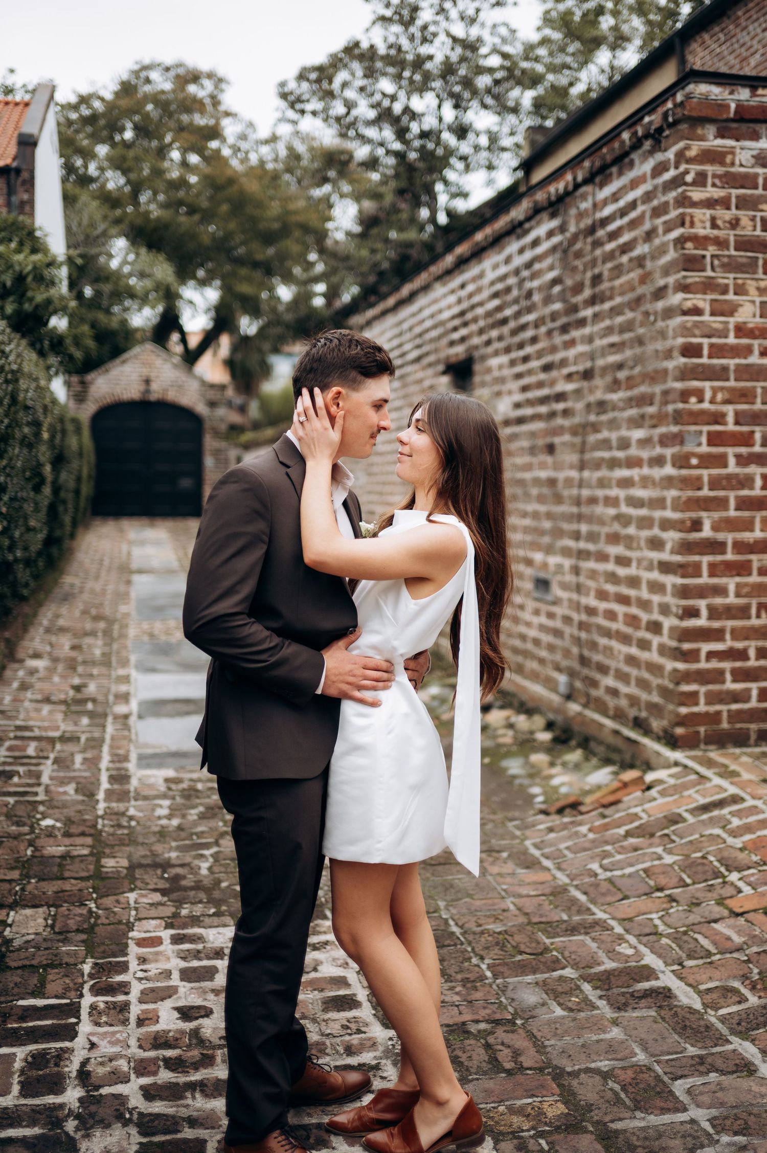 Intimate couple's photoshoot against rustic brick wall backdrop.