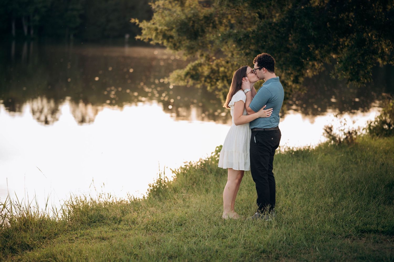 Golden hour light illuminates a romantic couple's photoshoot by the waterfront.
